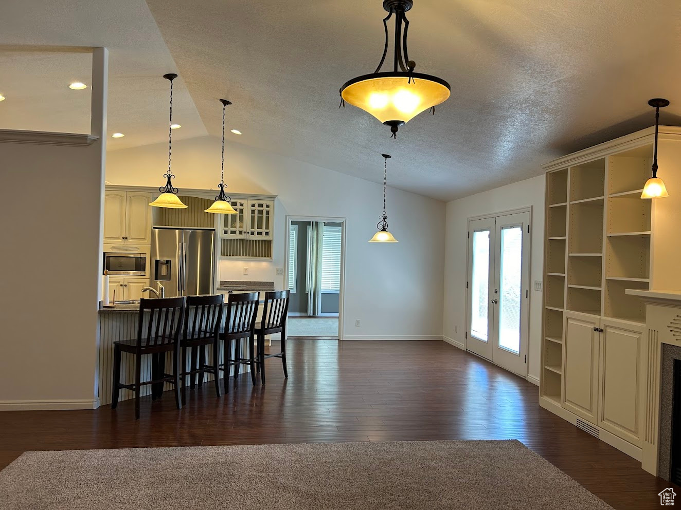 Kitchen featuring appliances with stainless steel finishes, pendant lighting, french doors, lofted ceiling, and dark wood-type flooring