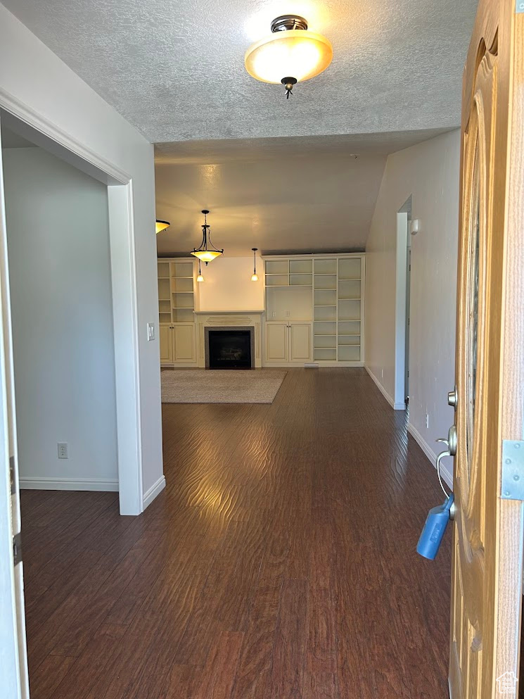 Unfurnished living room with dark wood-type flooring and a textured ceiling