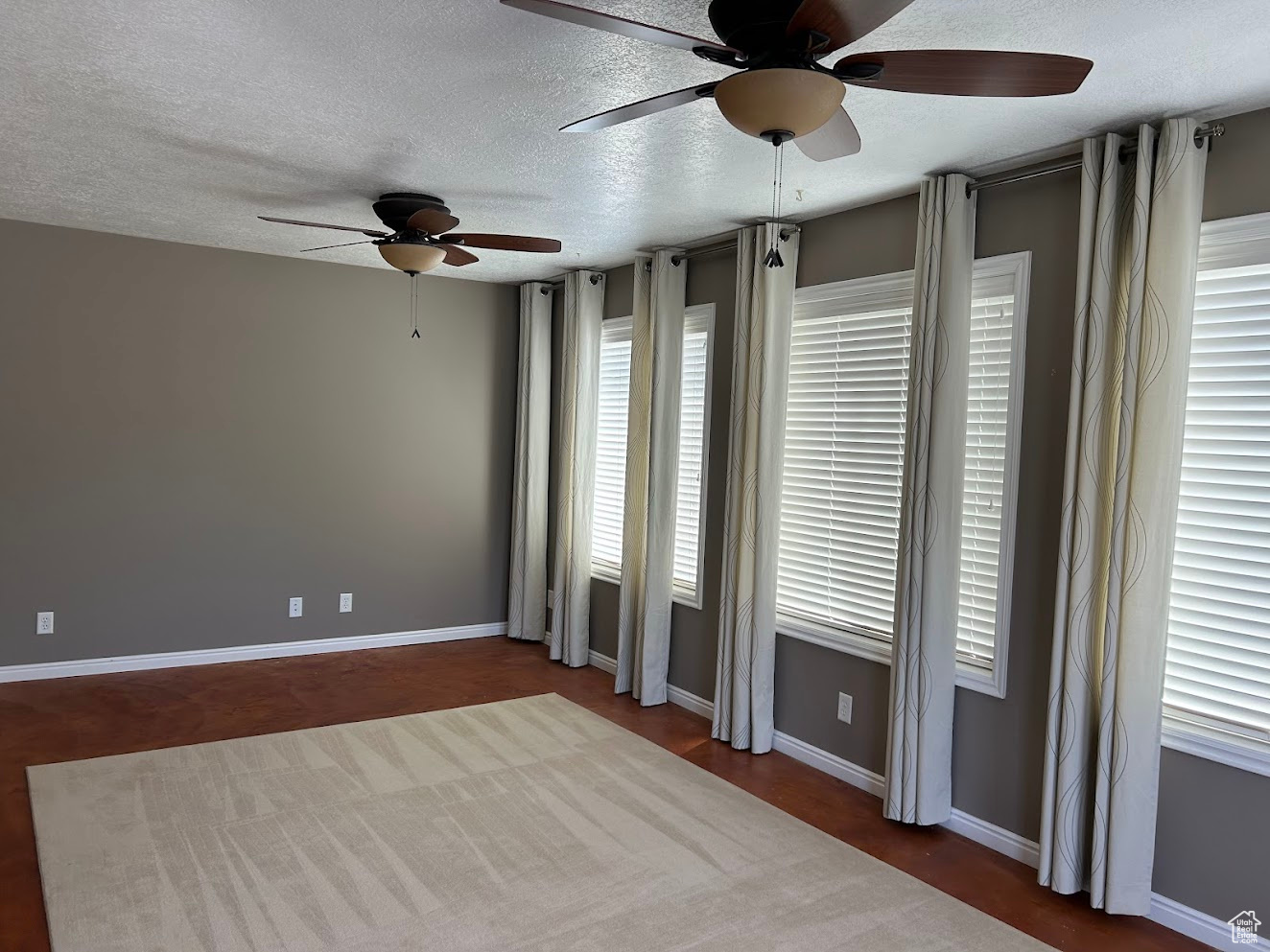 Empty room with a healthy amount of sunlight, a textured ceiling, and ceiling fan