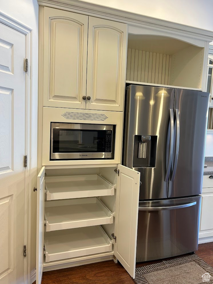 Kitchen featuring appliances with stainless steel finishes and dark wood-type flooring