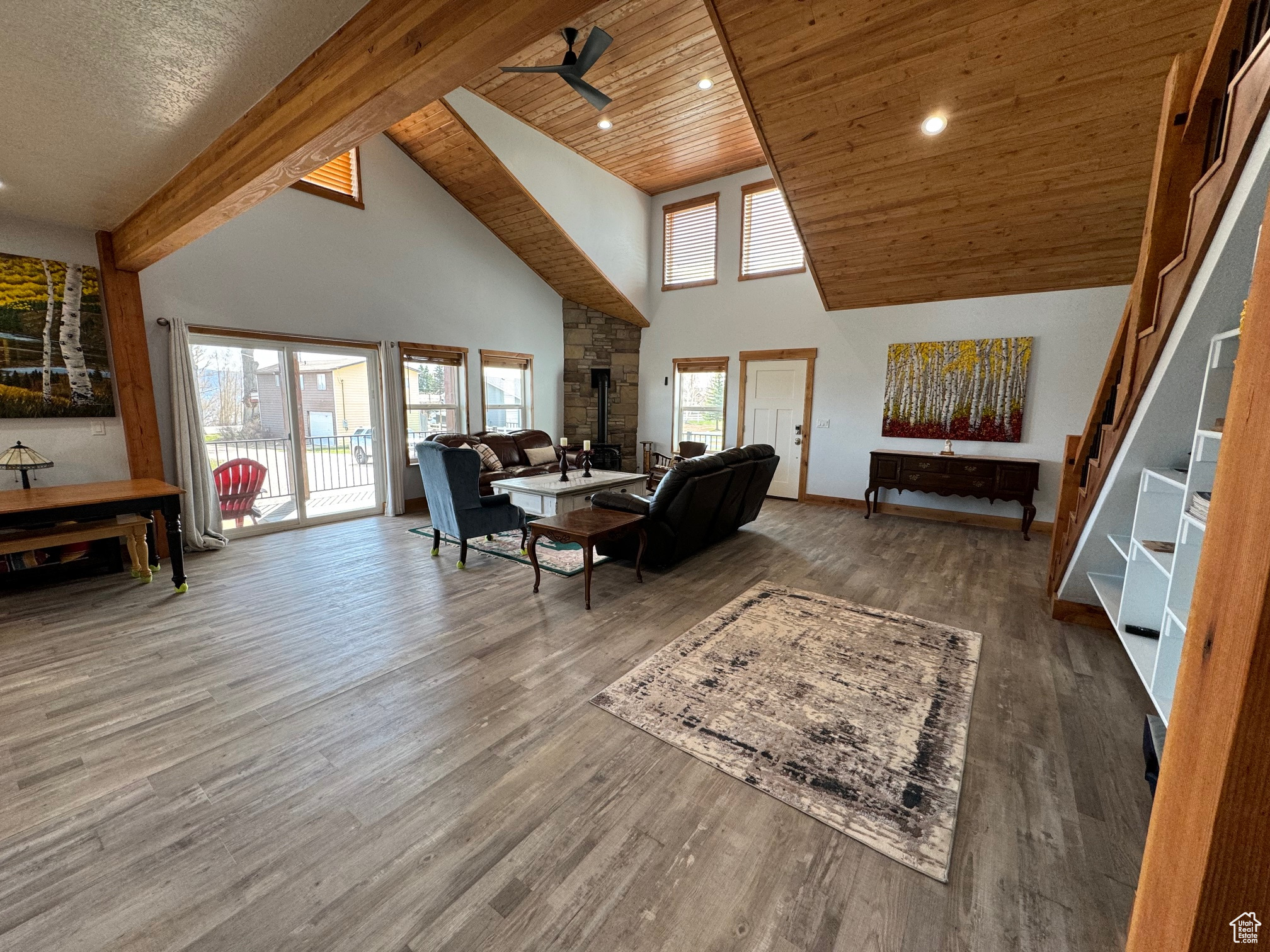 Living room featuring LVP flooring, high vaulted ceiling, wooden ceiling, beam ceiling, and ceiling fan