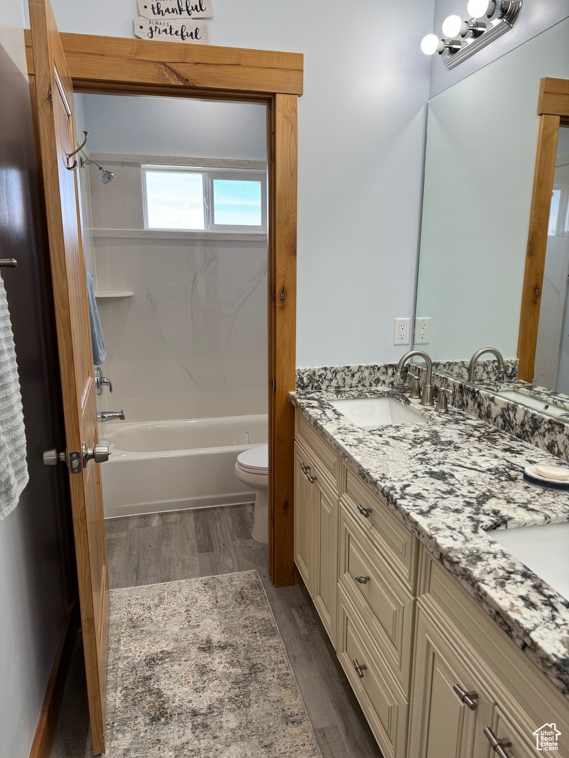Full bathroom featuring dual vanity, toilet, LVP floors, and shower / bathtub combination