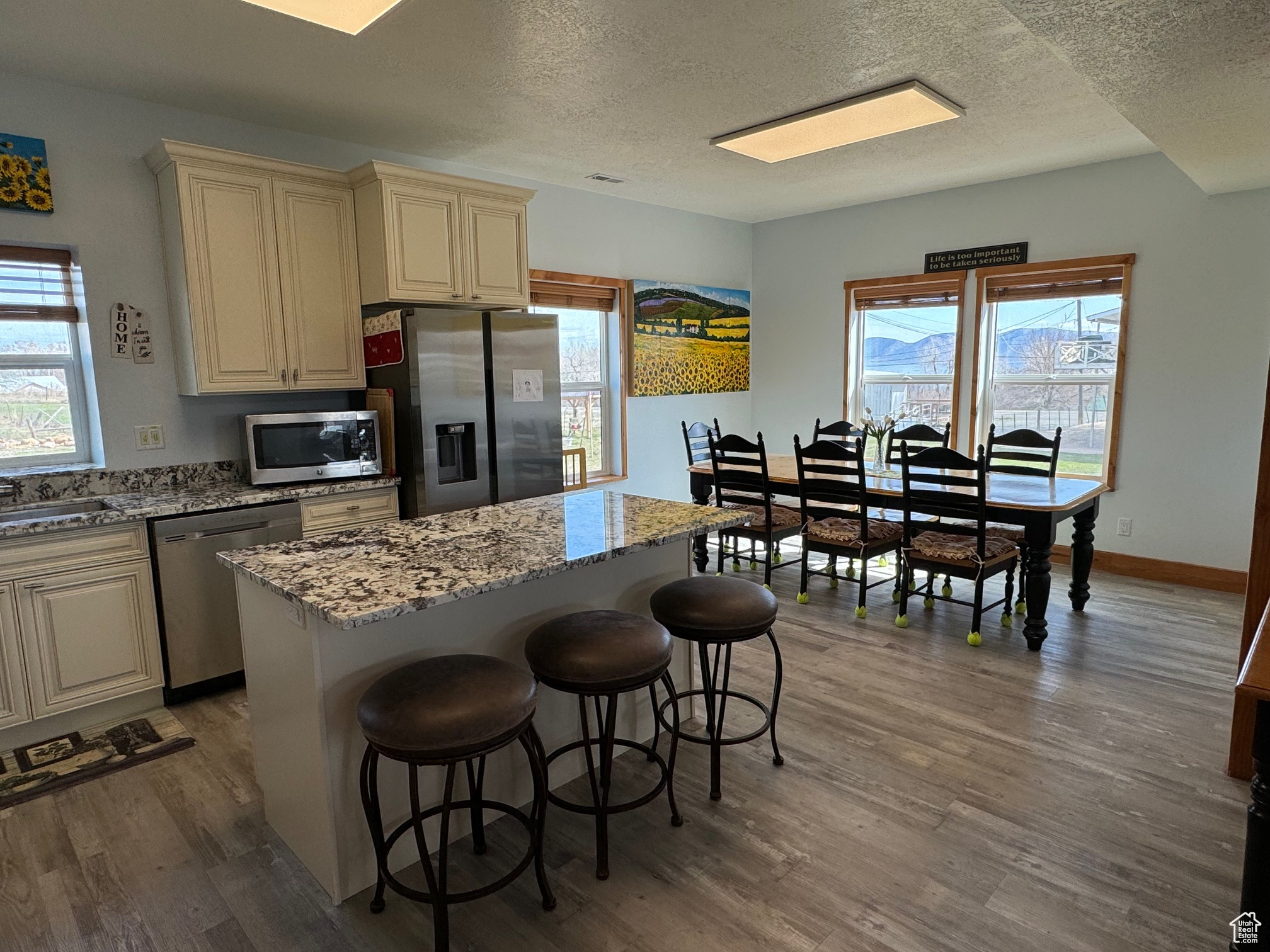 Kitchen with cream cabinets, a kitchen island,  stainless steel appliances, and LVP flooring
