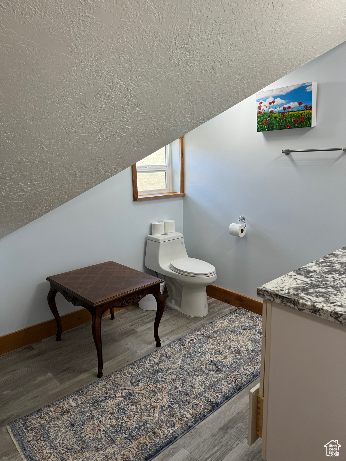 Bathroom with LVP flooring, vaulted ceiling, and toilet
