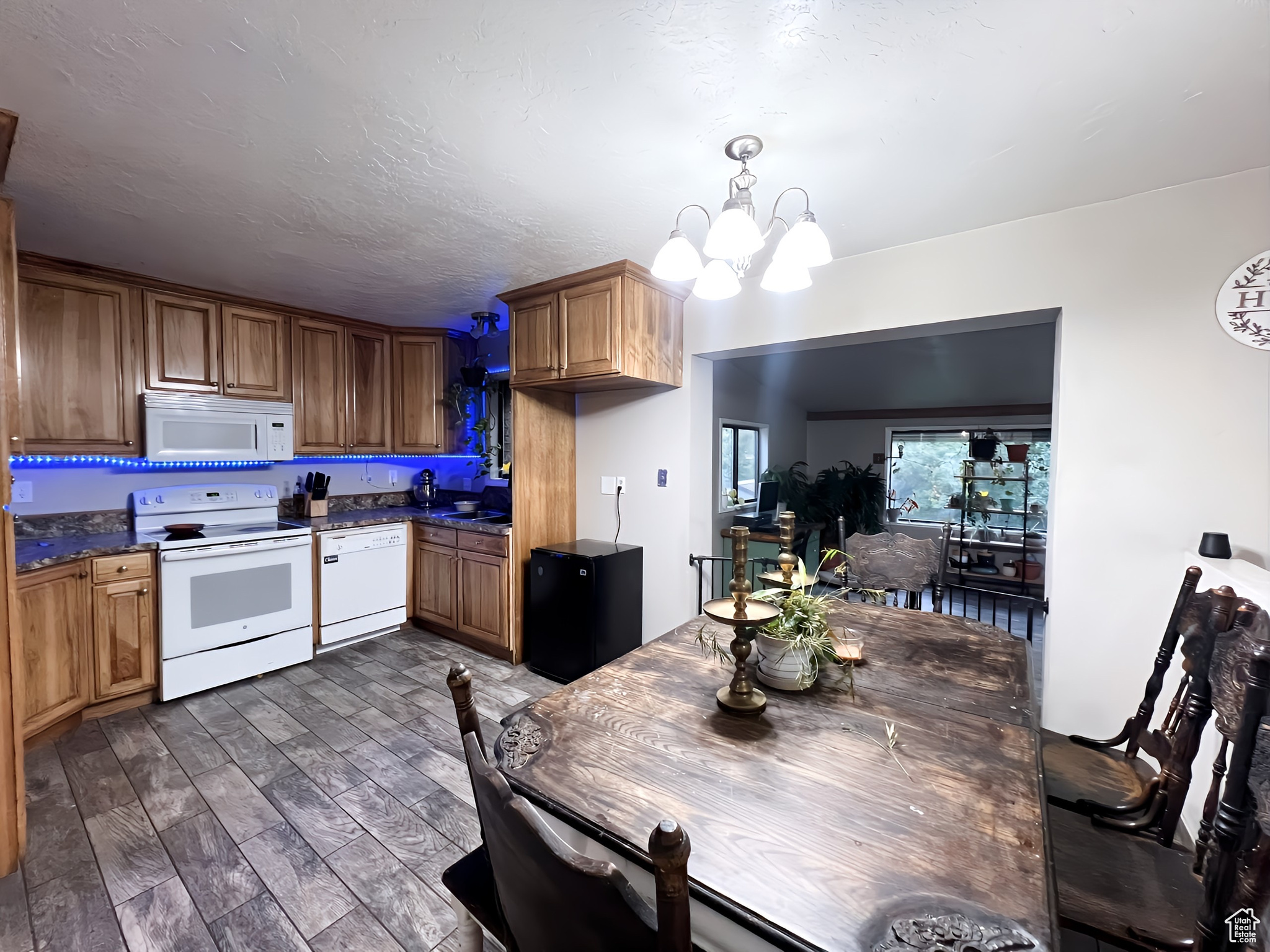 Kitchen featuring a textured ceiling, dark hardwood / wood-style floors, decorative light fixtures, white appliances, and a notable chandelier