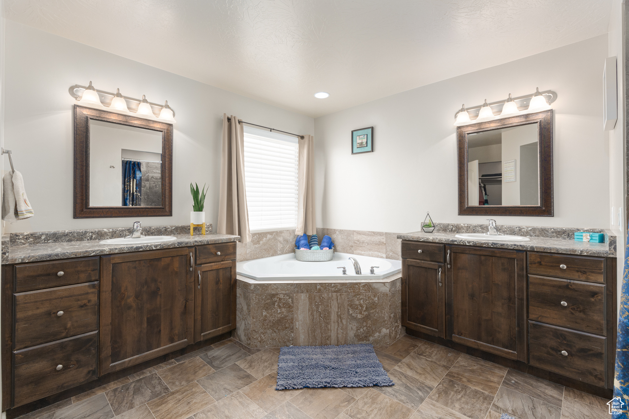 Bathroom featuring dual bowl vanity, tile floors, and tiled bath