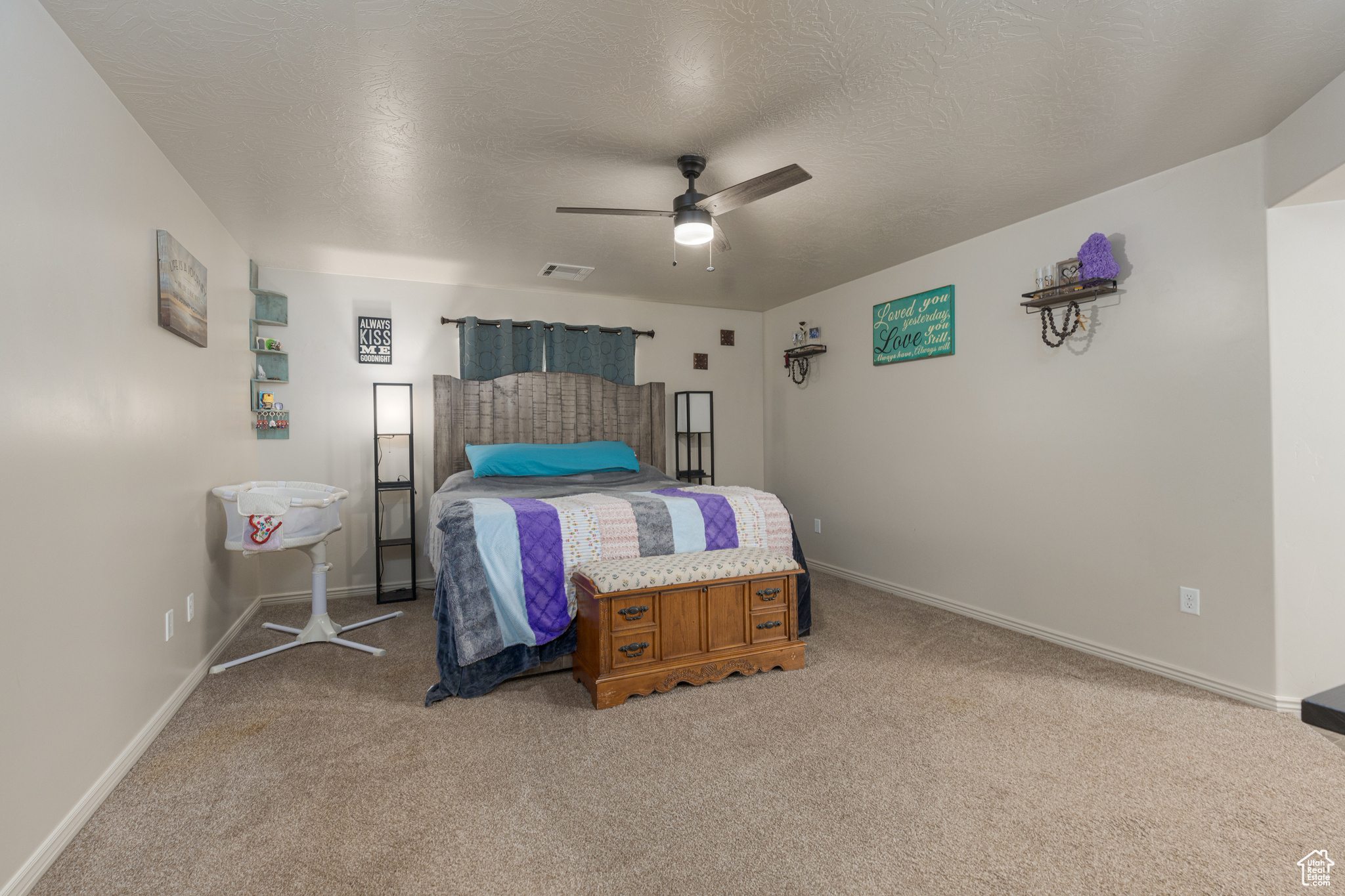 Carpeted bedroom featuring ceiling fan and a textured ceiling