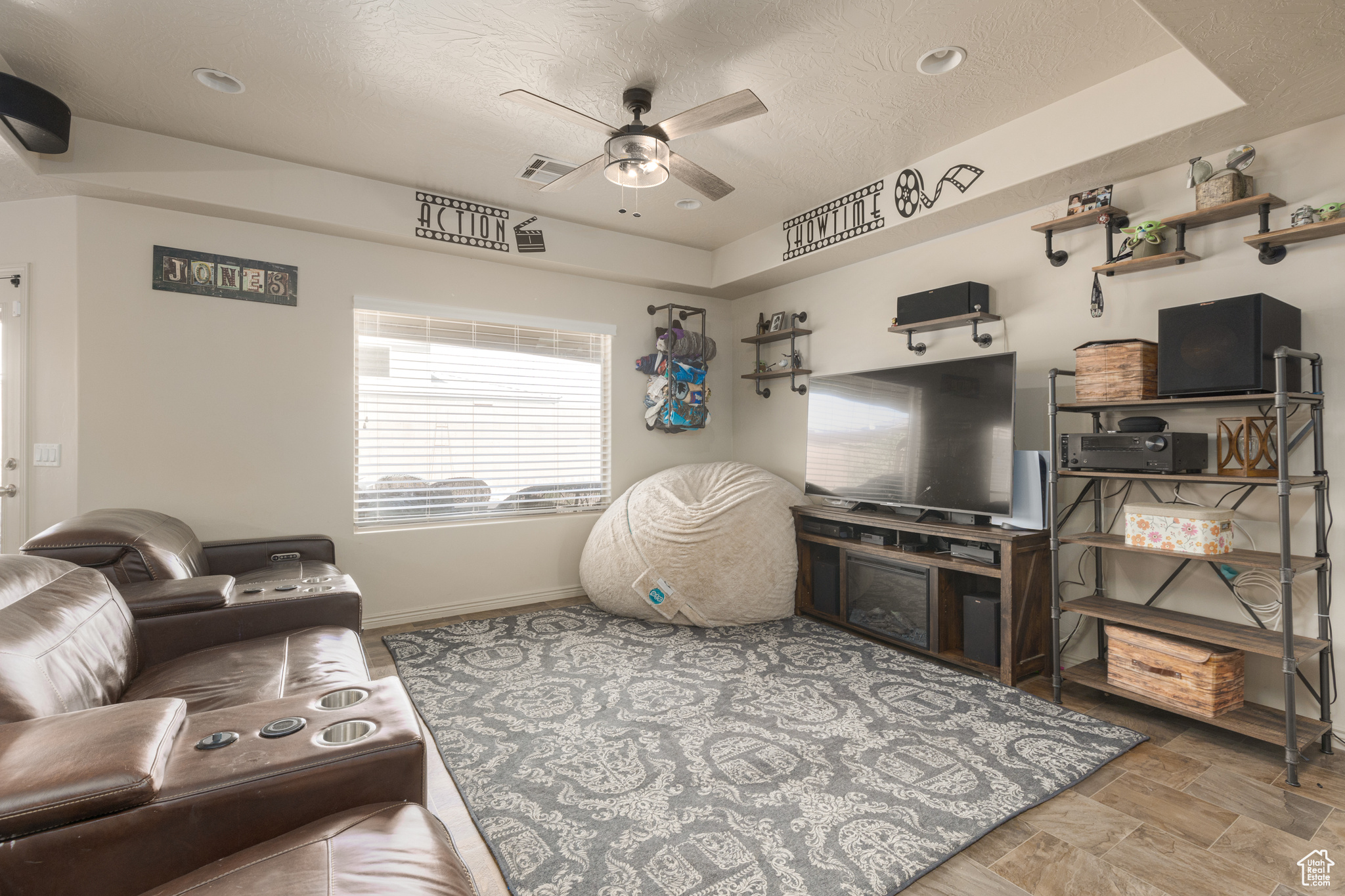 Living room with a textured ceiling, a raised ceiling, and ceiling fan