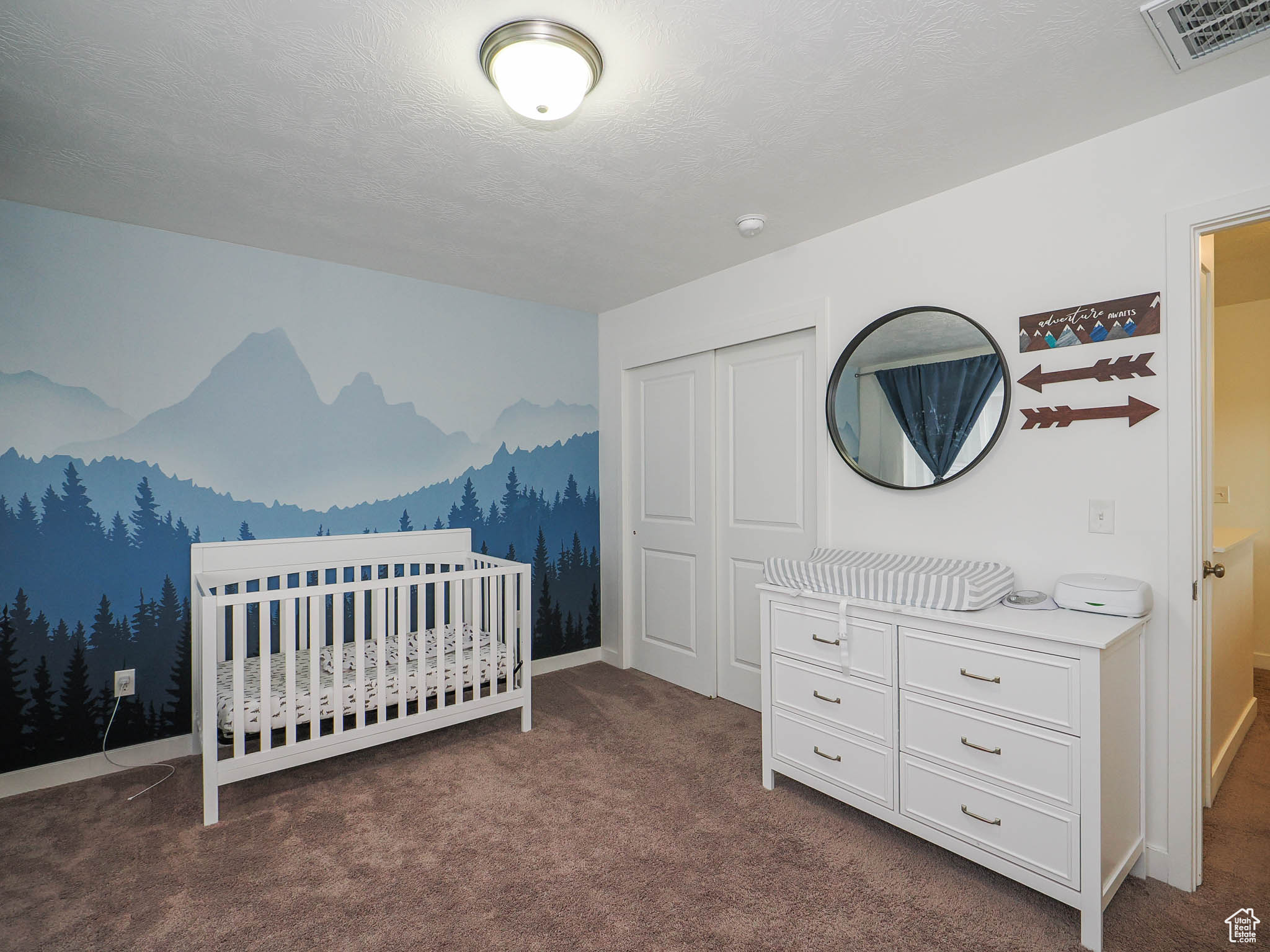 Carpeted bedroom with a crib and a closet