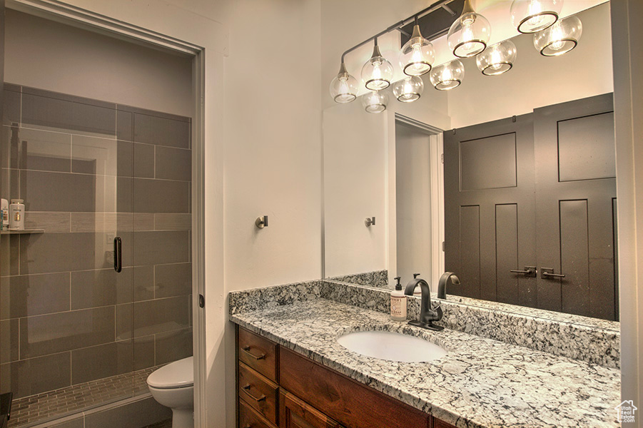 Bathroom with a shower with door, vanity, and toilet.