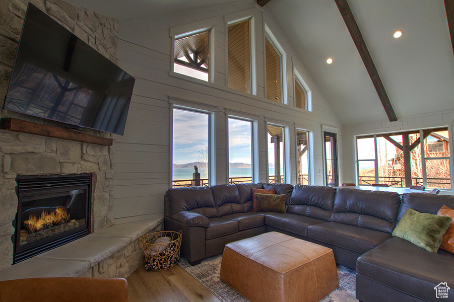 Living room with a wealth of natural light, wood-type flooring, beam ceiling, and a fireplace