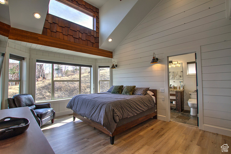 Main floor master bedroom featuring hardwood / wood-style floors, connected bathroom, and multiple windows