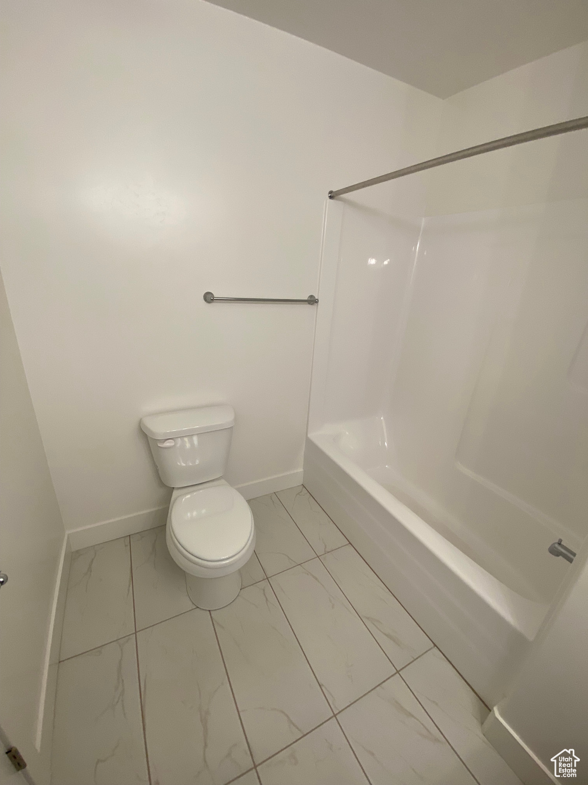 Bathroom with shower / bathing tub combination, tile floors, and toilet