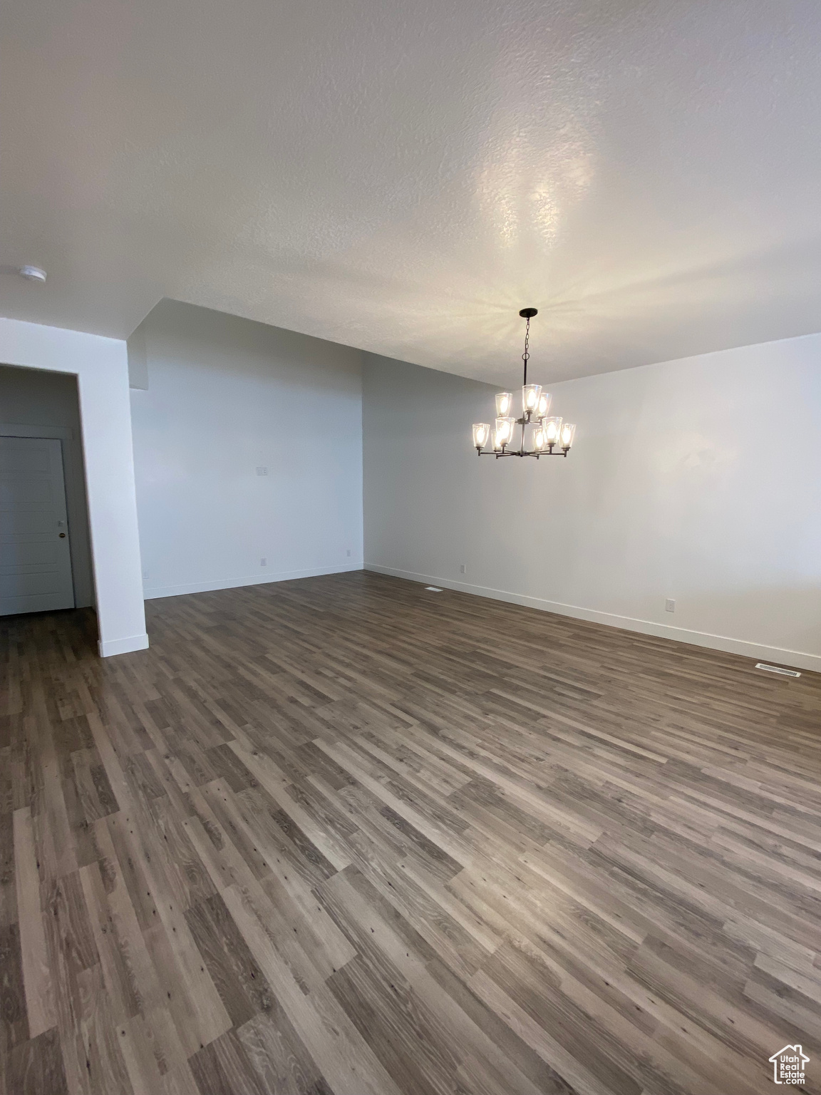 Spare room with dark hardwood / wood-style floors, a chandelier, and a textured ceiling
