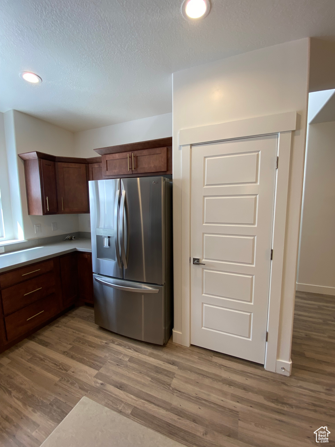 Kitchen with hardwood / wood-style flooring, stainless steel fridge with ice dispenser, and a textured ceiling