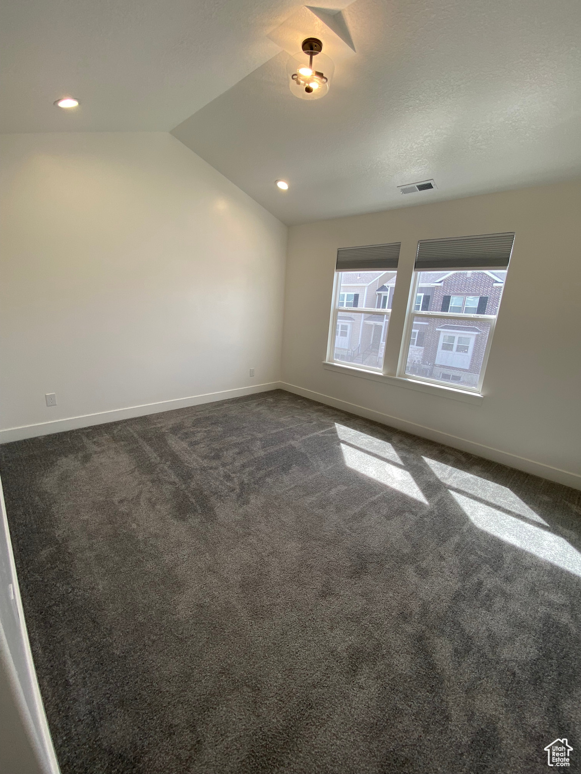 Spare room with dark carpet and vaulted ceiling