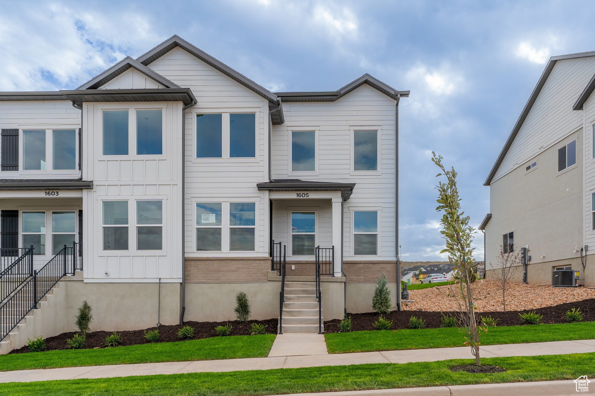 View of front of home with central AC unit and a front lawn