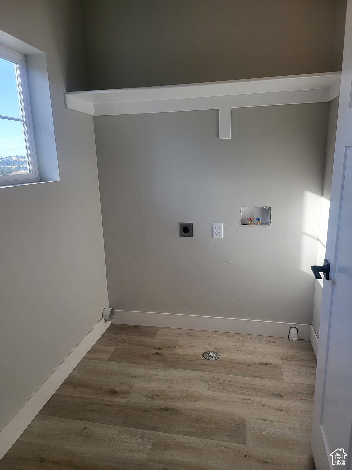 Washroom with washer hookup, electric dryer hookup, and light hardwood / wood-style floors