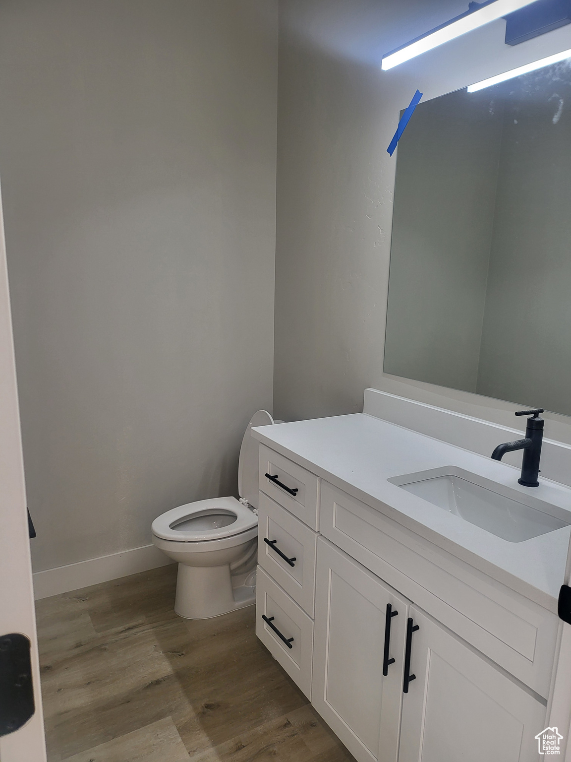 1/2 Bathroom with wood-type flooring, toilet, and vanity