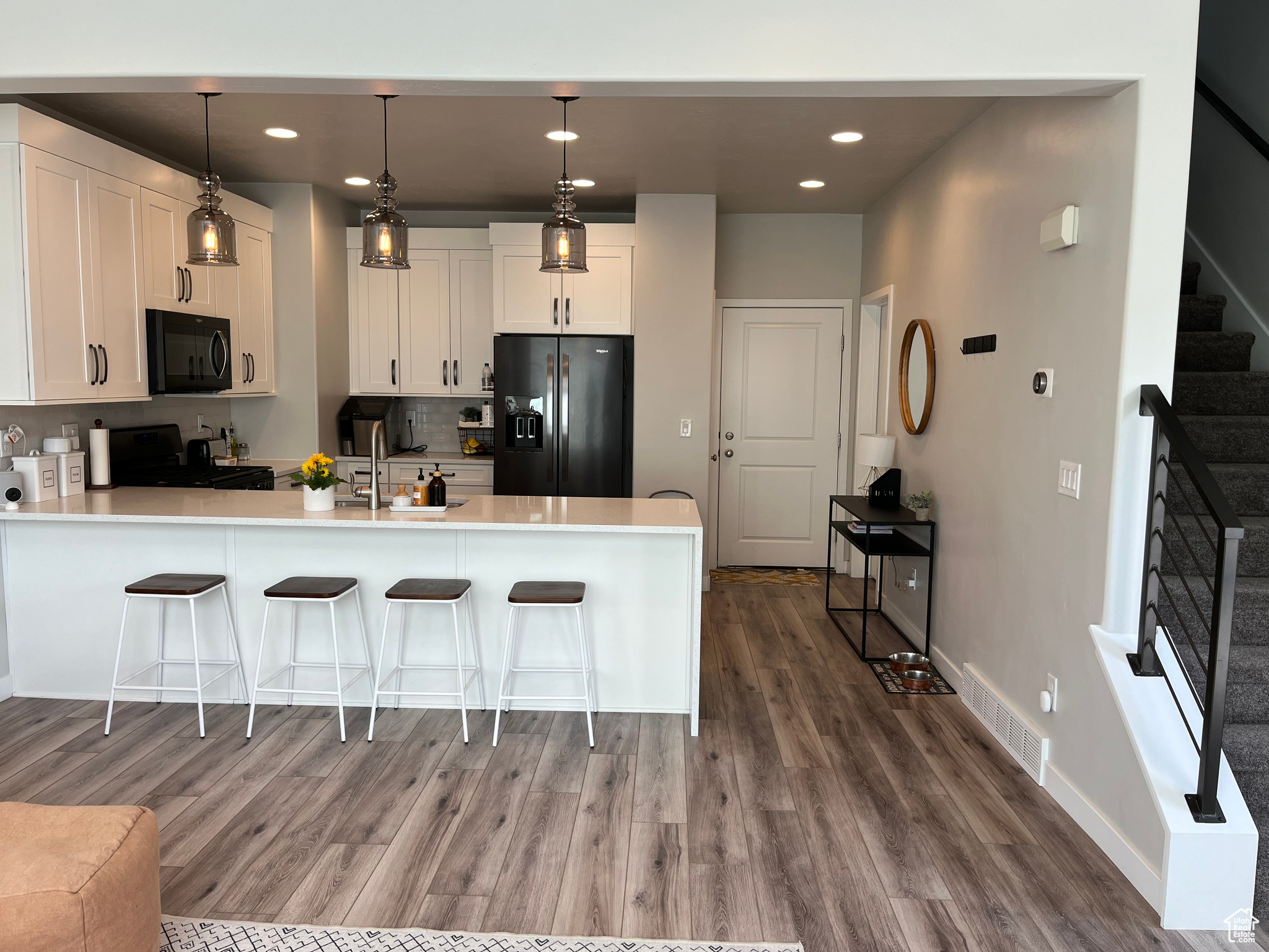 Kitchen featuring hardwood / wood-style flooring, white cabinetry, stainless steel fridge, and range
