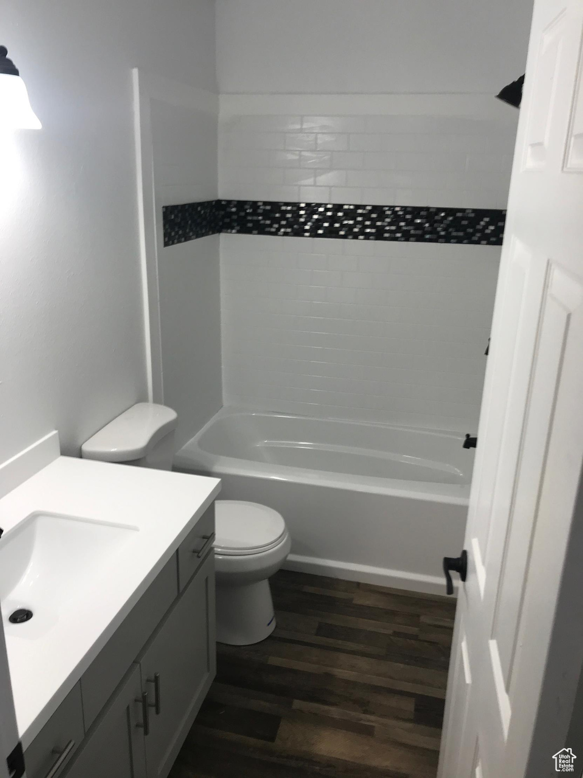 Full bathroom featuring tiled shower / bath combo, wood-type flooring, vanity, and toilet