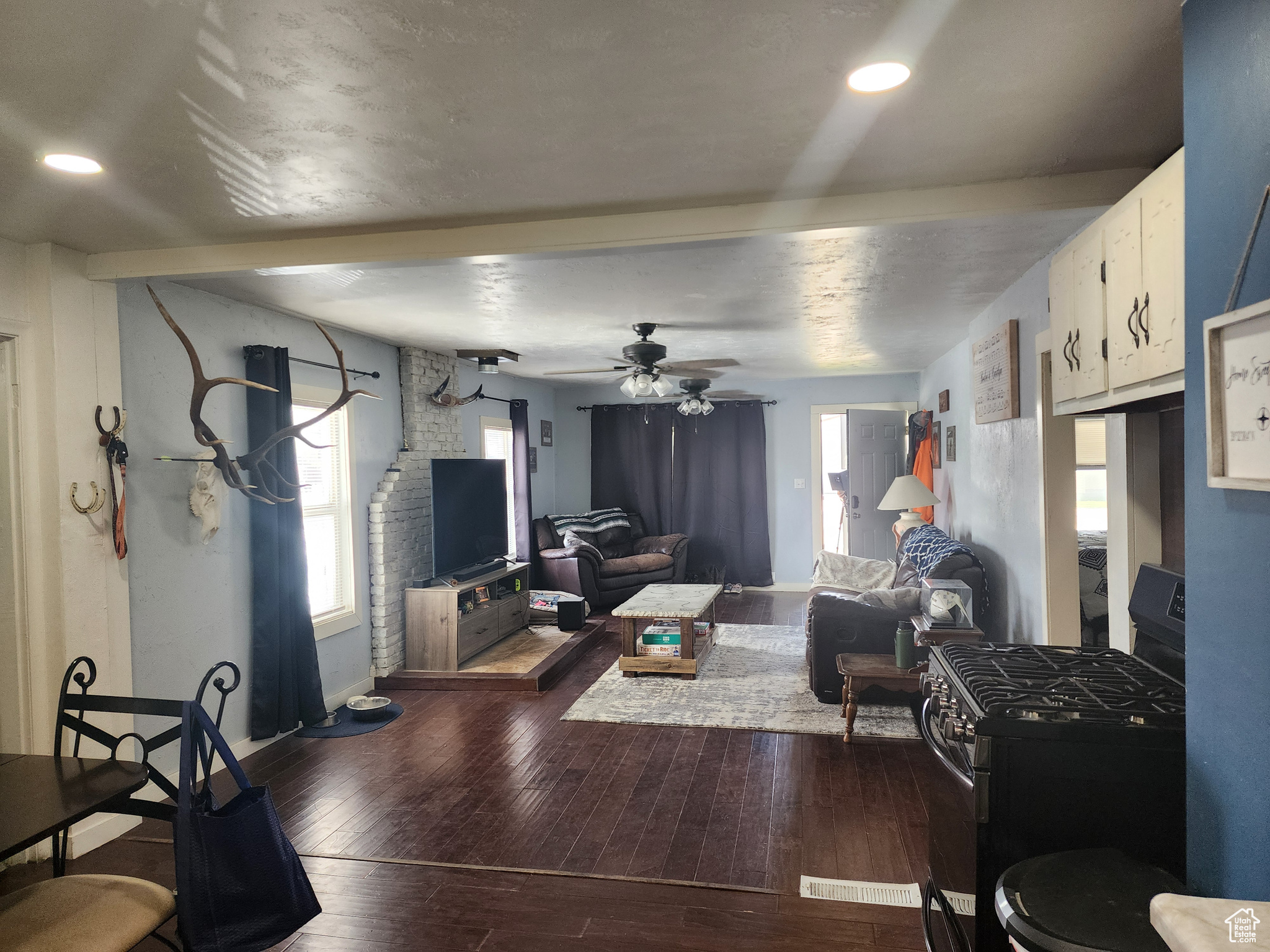 Living room with wood-type flooring, ceiling fan, and a healthy amount of sunlight