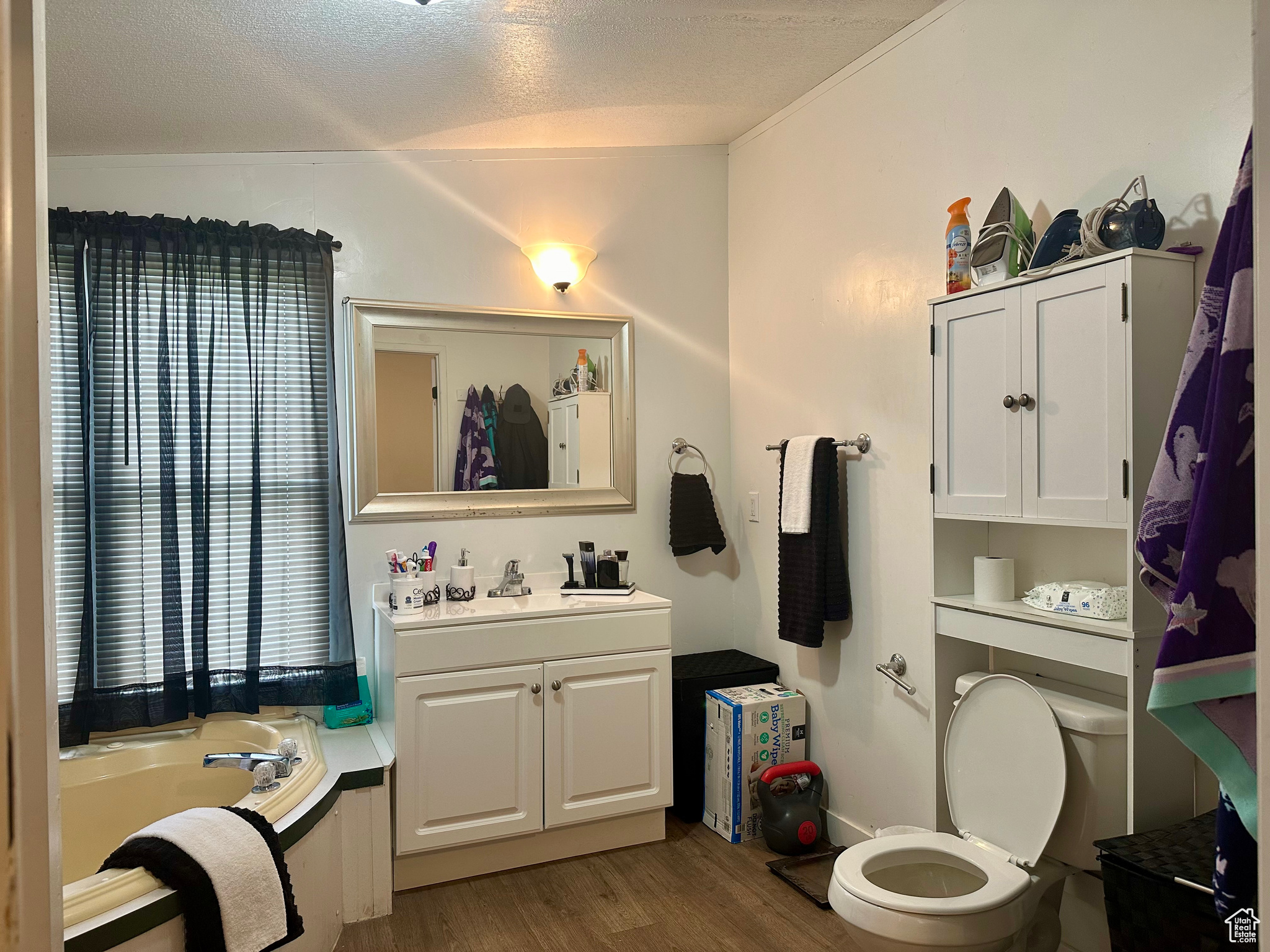 Bathroom featuring a bath, a textured ceiling, oversized vanity, toilet, and hardwood / wood-style flooring