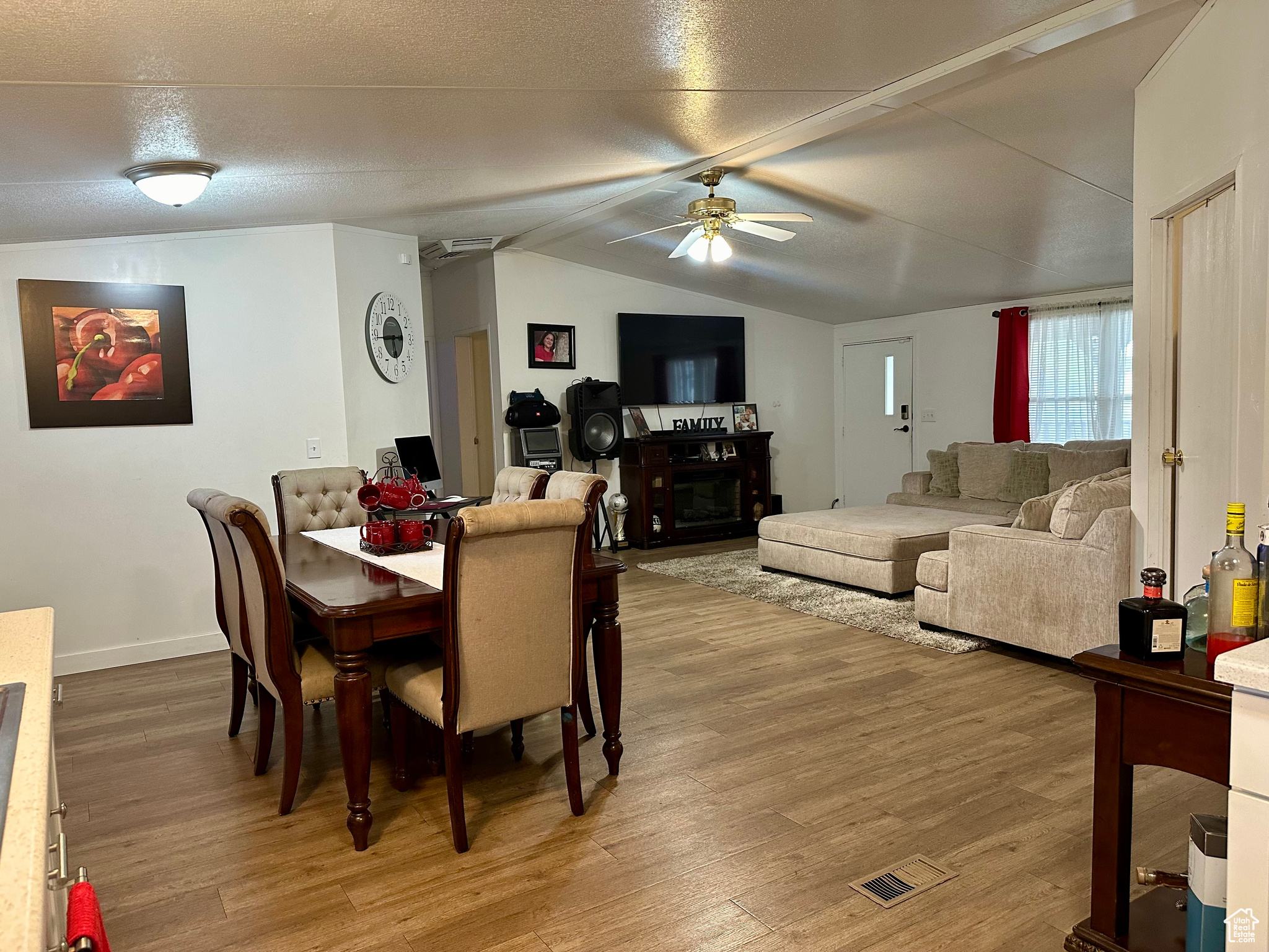 Dining room featuring hardwood / wood-style flooring, a textured ceiling, ceiling fan, and vaulted ceiling