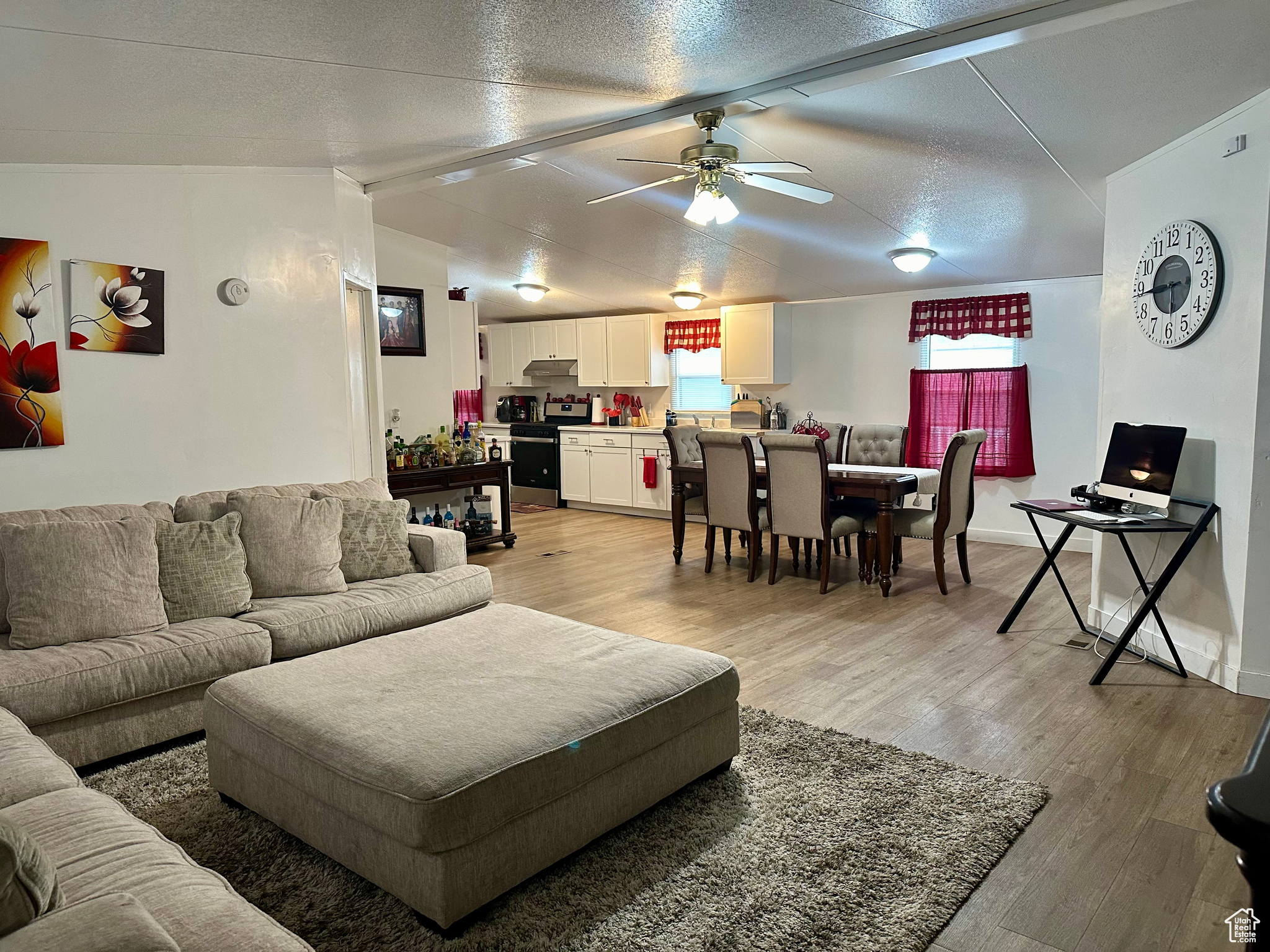 Living room featuring hardwood / wood-style flooring, ceiling fan, a textured ceiling, and lofted ceiling