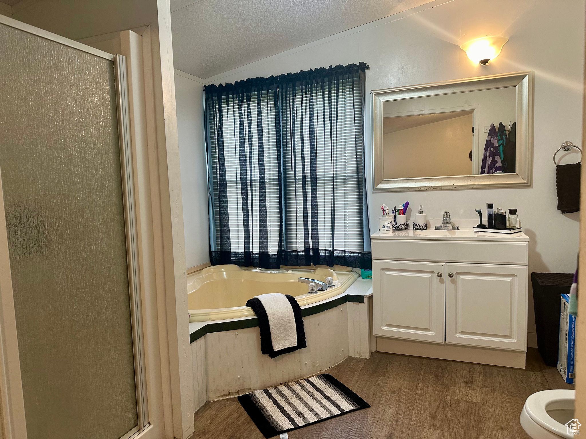 Full bathroom with crown molding, toilet, wood-type flooring, vanity, and plus walk in shower