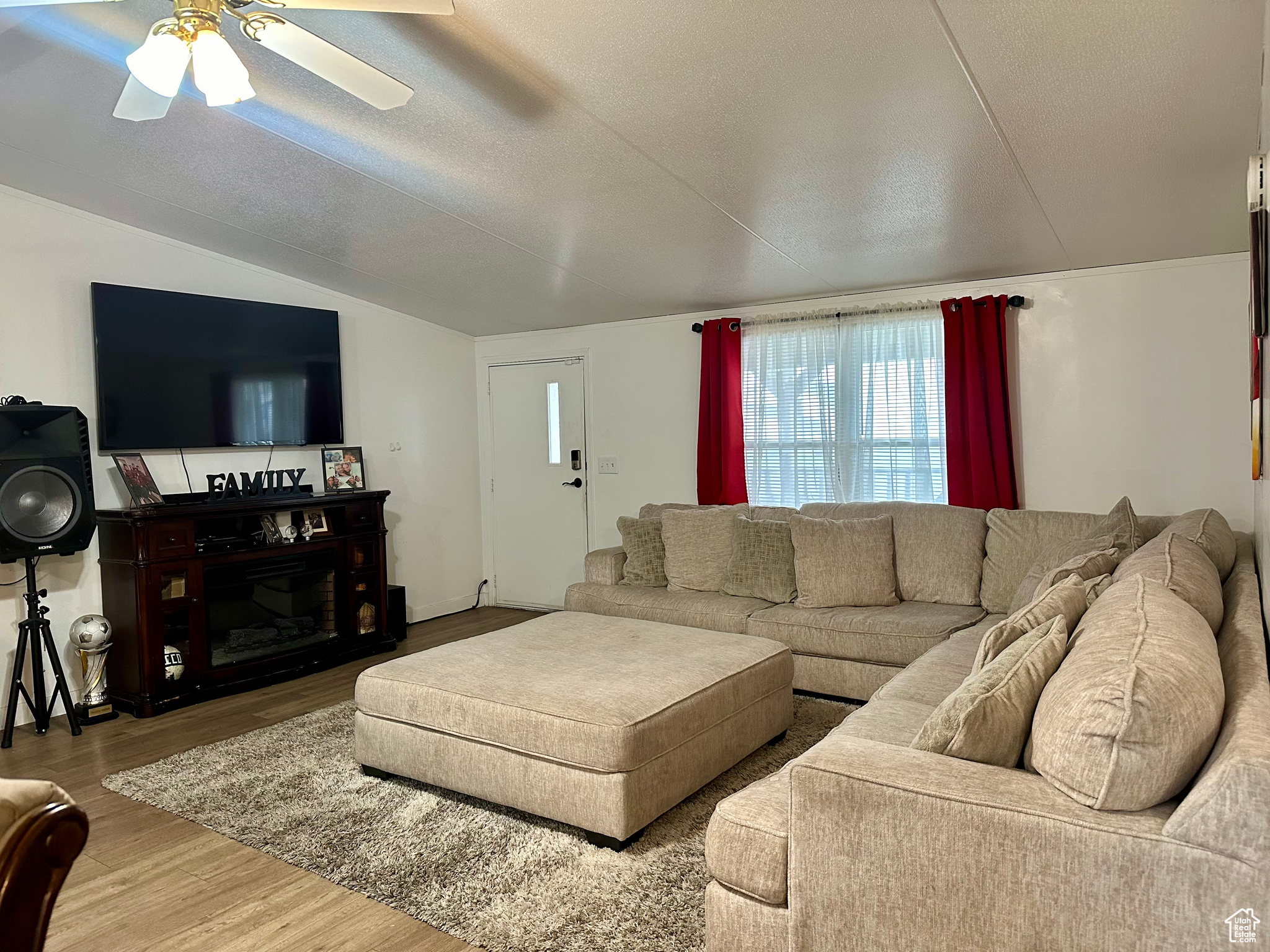 Living room with wood-type flooring, ceiling fan, a textured ceiling, and lofted ceiling