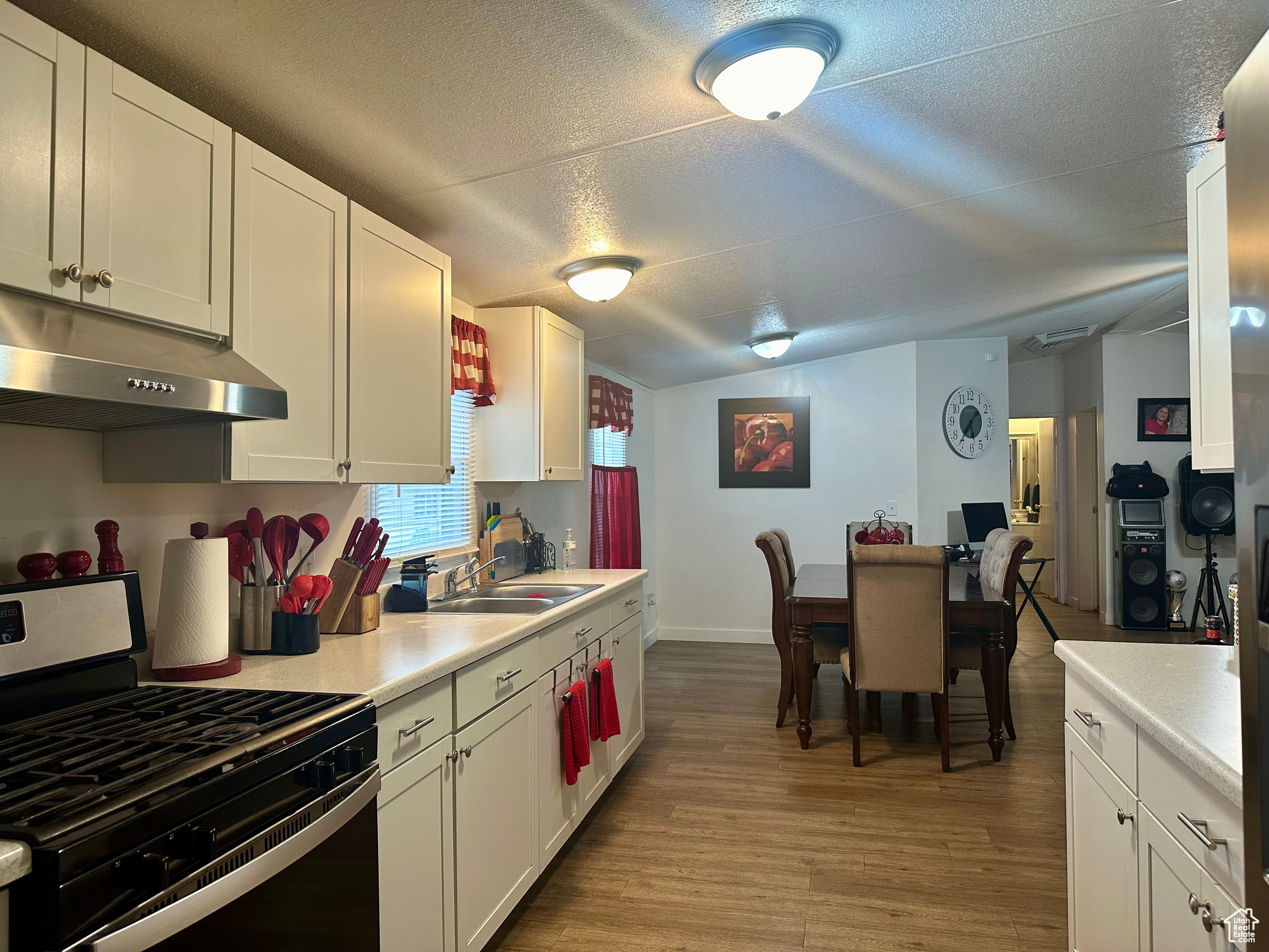 Kitchen featuring white cabinets, sink, stainless steel range with gas cooktop, and light wood-type flooring