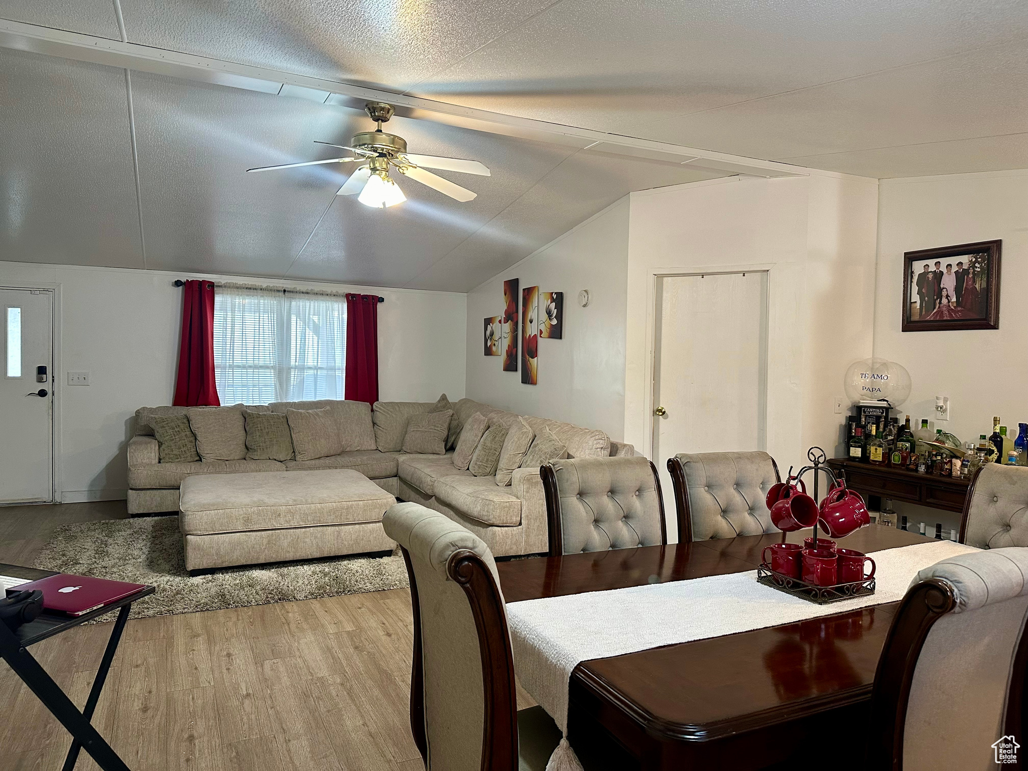 Dining space with lofted ceiling, ceiling fan, light hardwood / wood-style flooring, and a textured ceiling