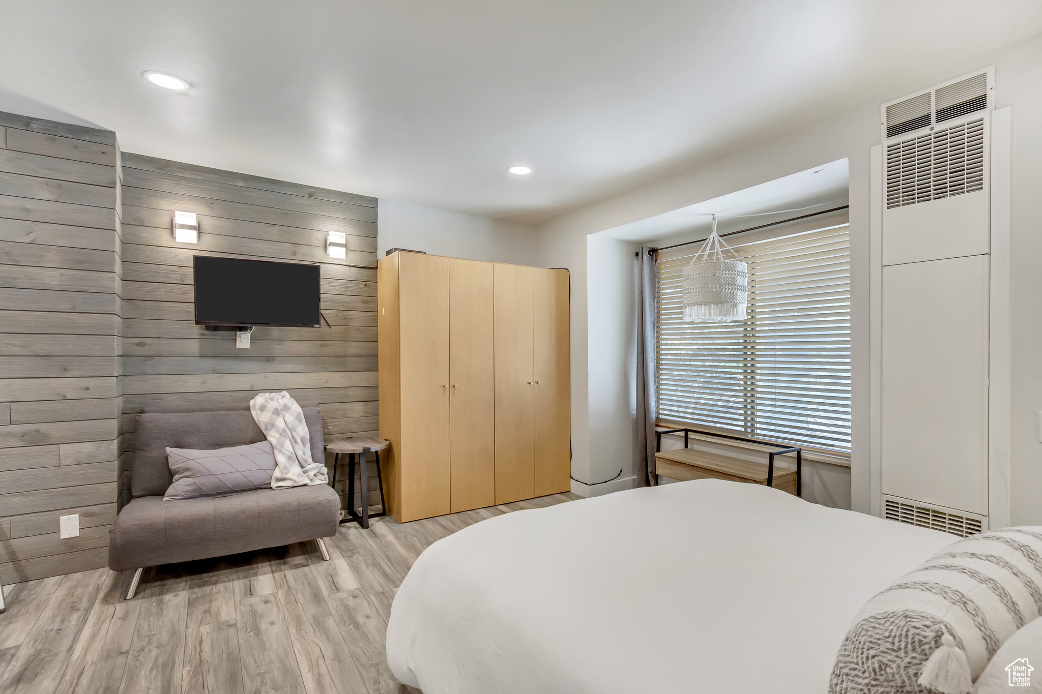 Bedroom with light wood-type flooring and wood walls