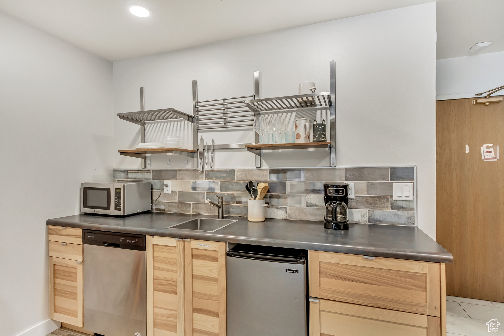 Kitchen featuring tasteful backsplash, light tile flooring, light brown cabinetry, sink, and appliances with stainless steel finishes