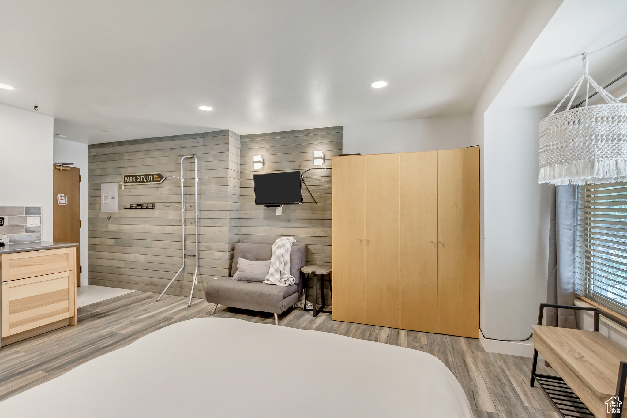 Bedroom with wooden walls and light hardwood / wood-style flooring