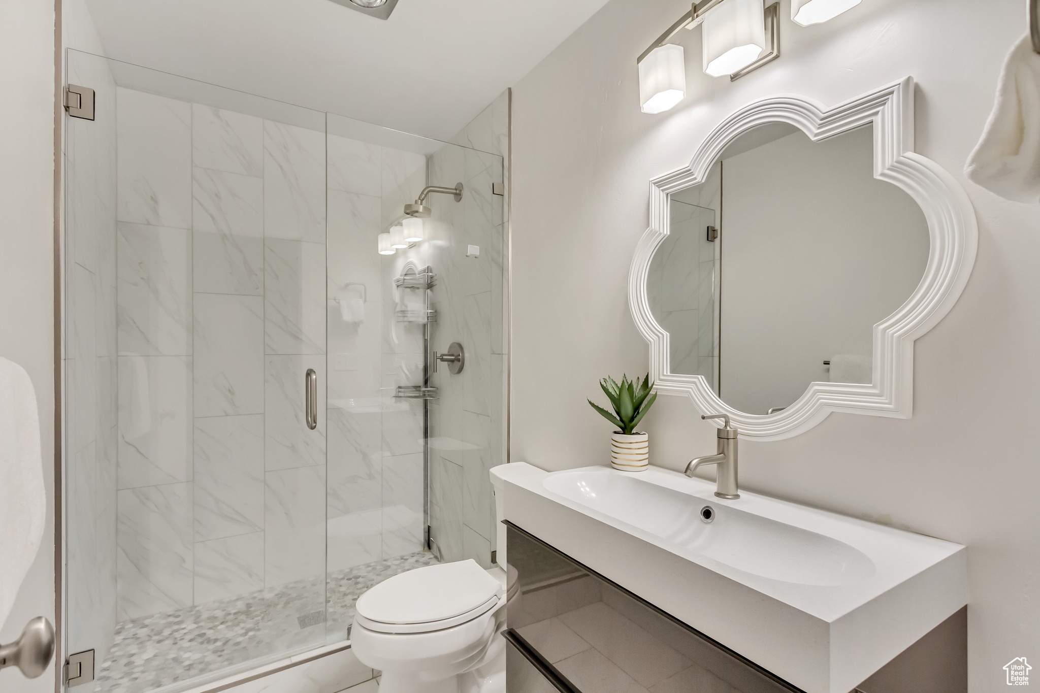 Bathroom featuring tile floors, a shower with door, vanity, and toilet