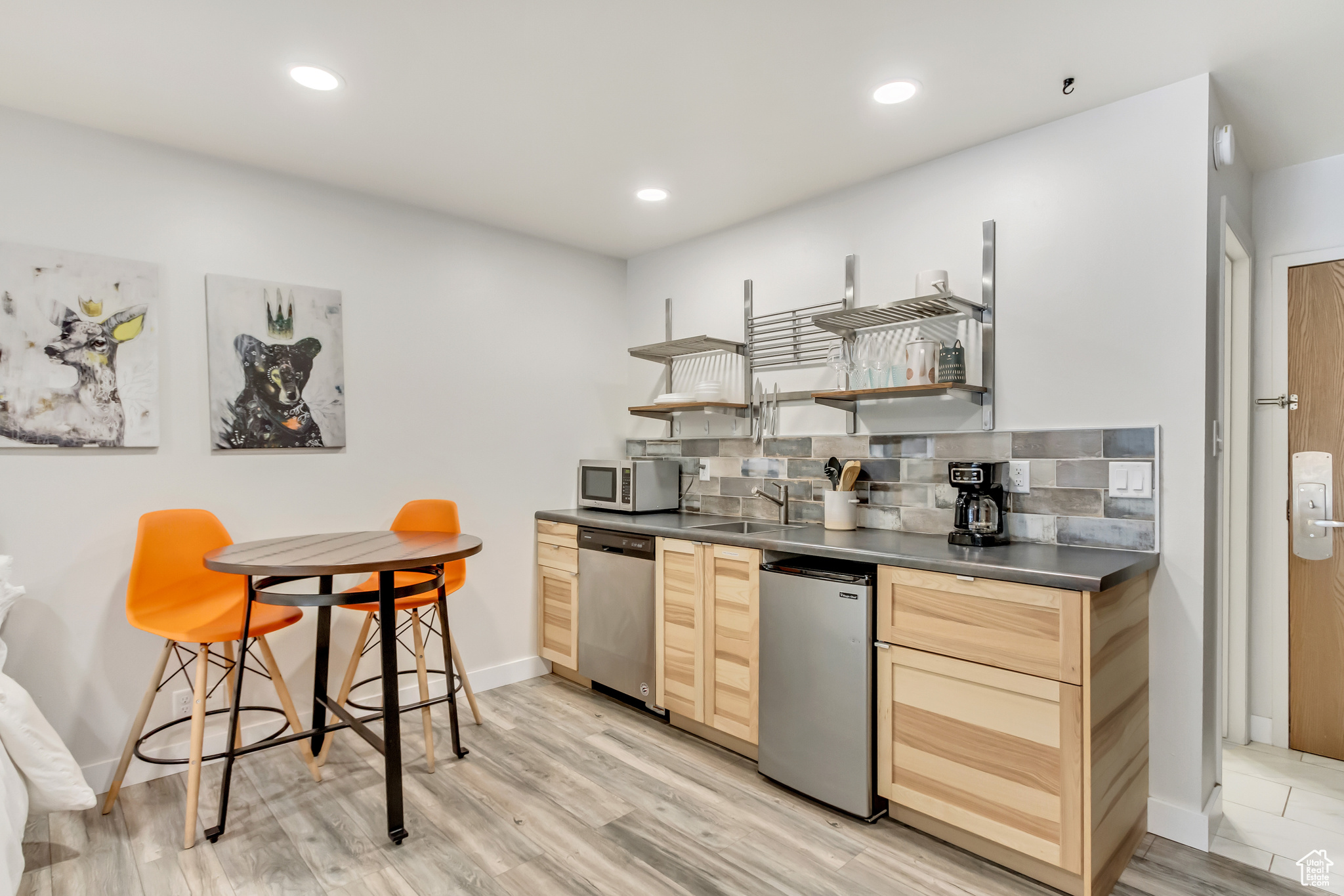 Kitchen featuring stainless steel appliances, light hardwood / wood-style flooring, sink, tasteful backsplash, and light brown cabinets