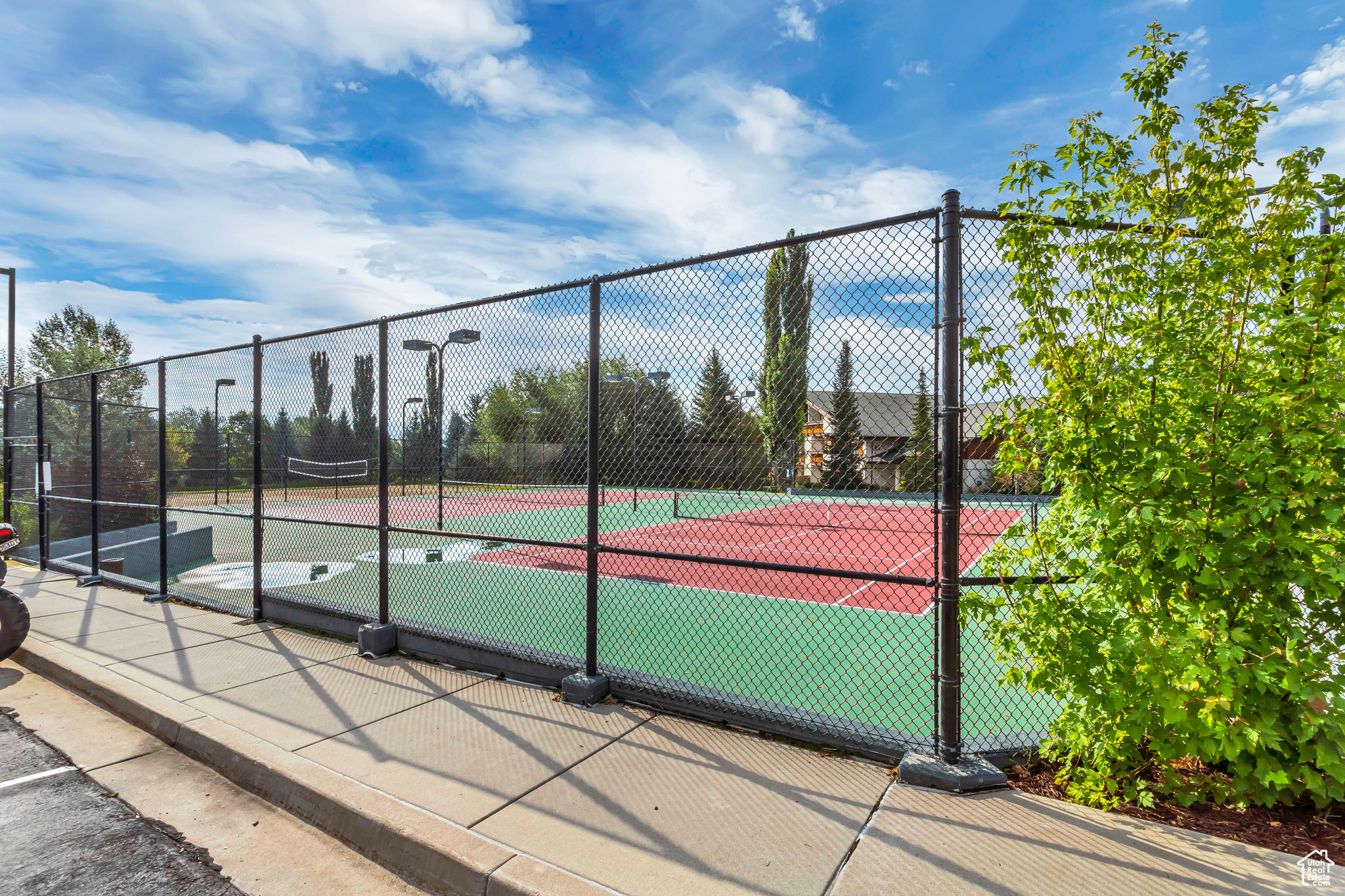 View of tennis court featuring basketball hoop