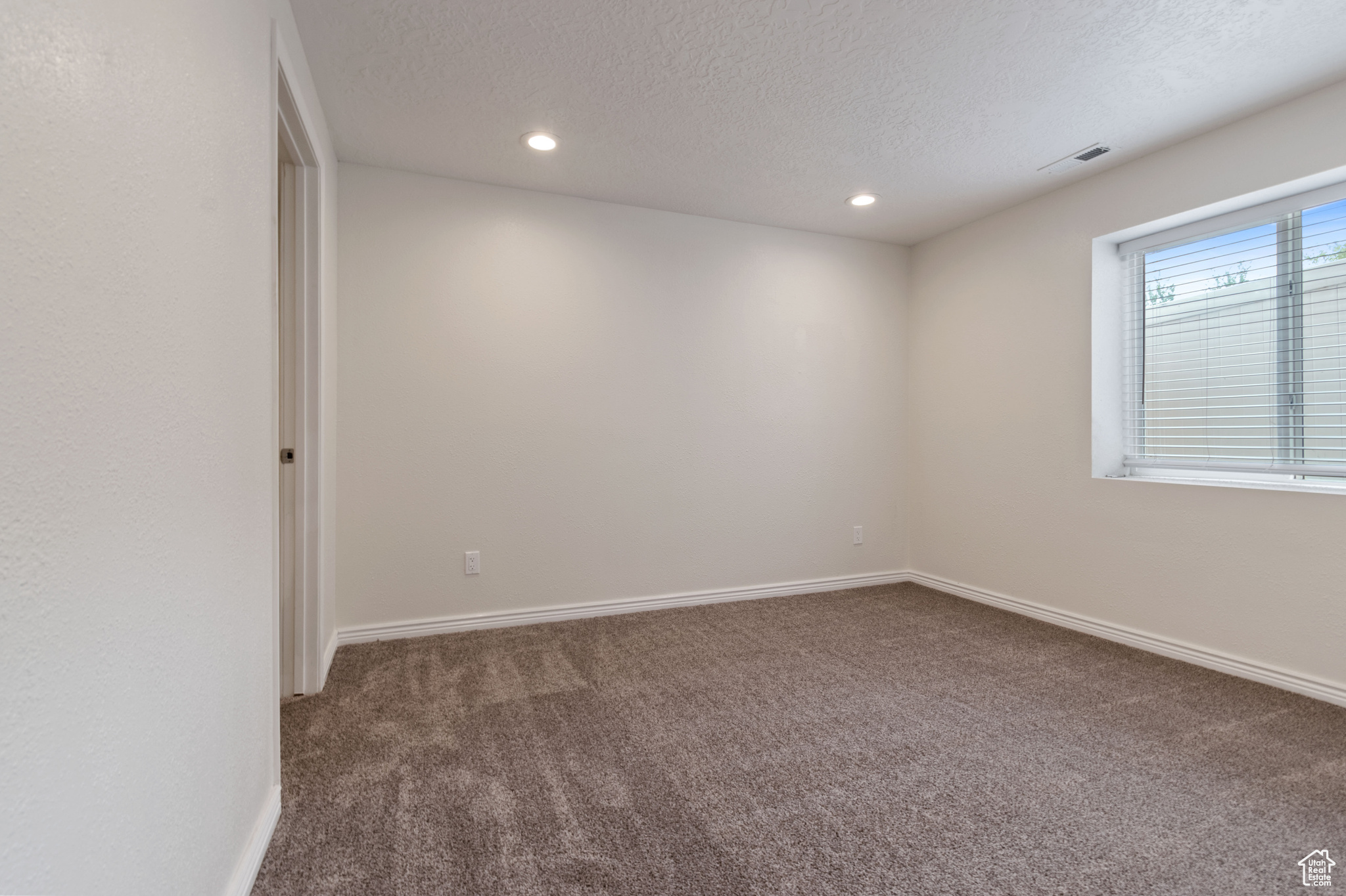 Empty room featuring a textured ceiling and carpet flooring