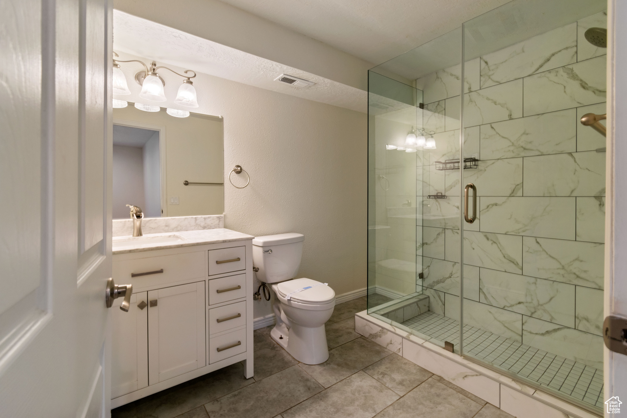 Bathroom with vanity with extensive cabinet space, a shower with door, and tile flooring