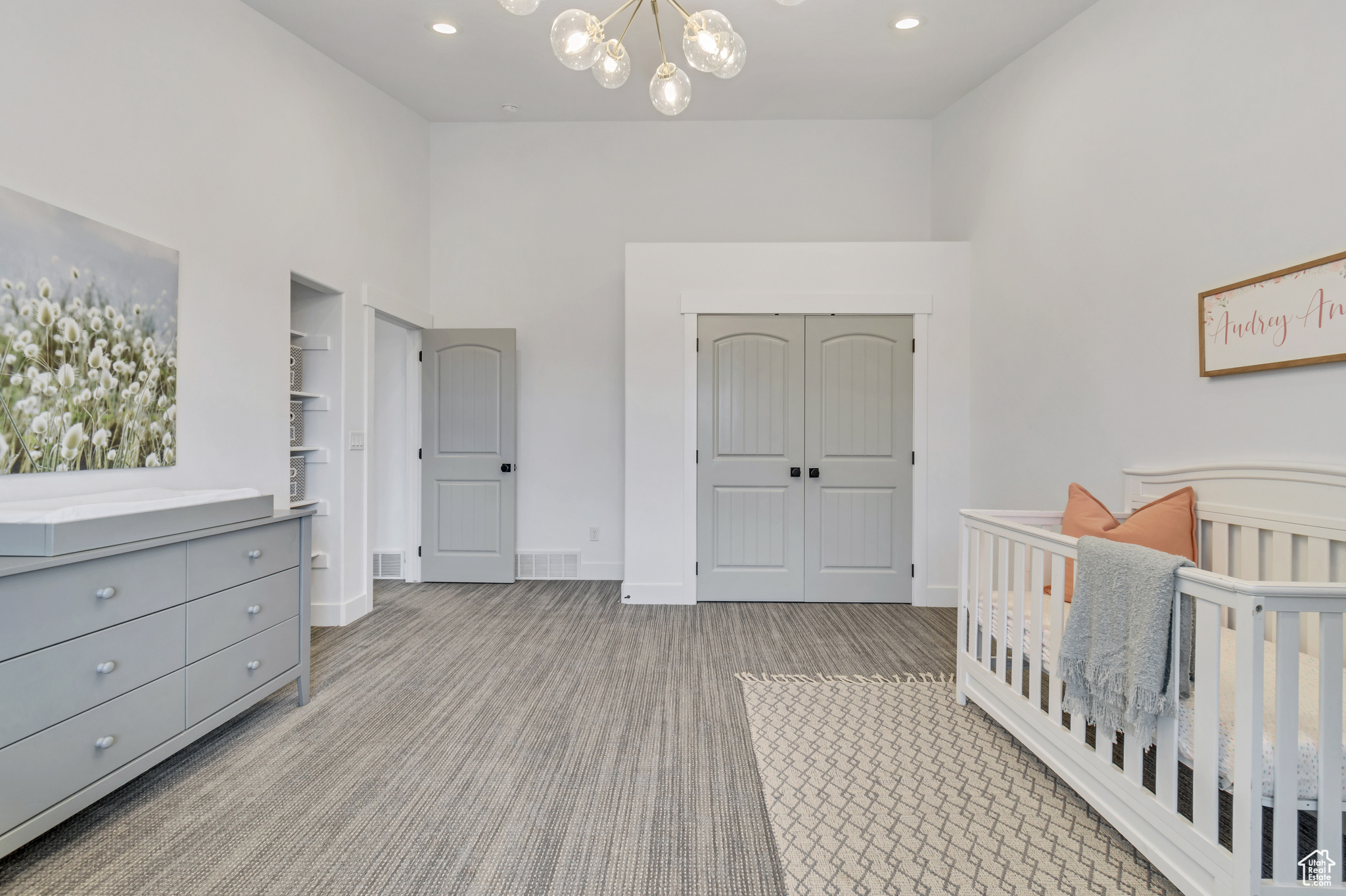 Bedroom featuring light carpet, a closet, an inviting chandelier, a nursery area, and a towering ceiling