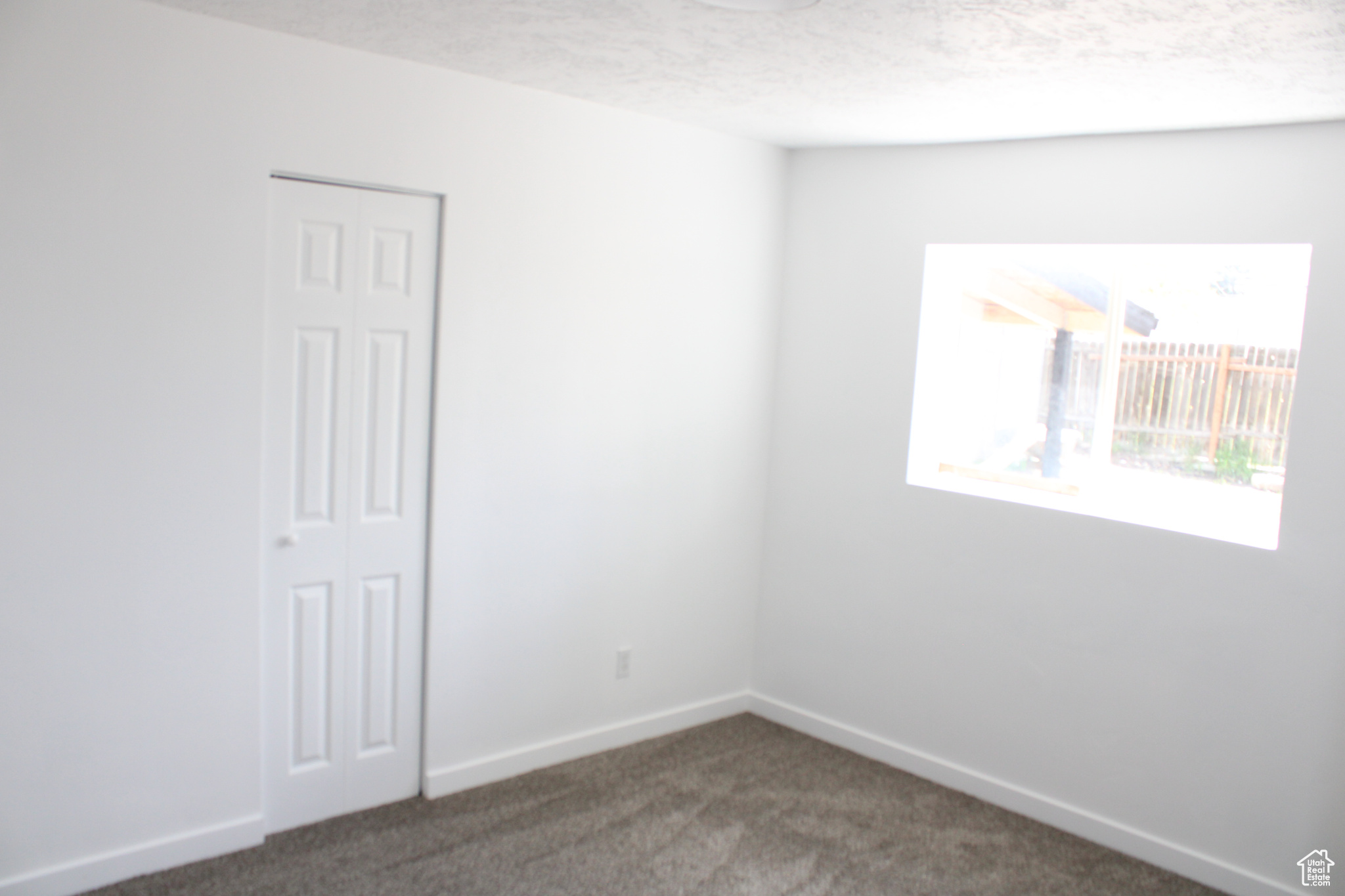 Unfurnished room with a textured ceiling and dark carpet