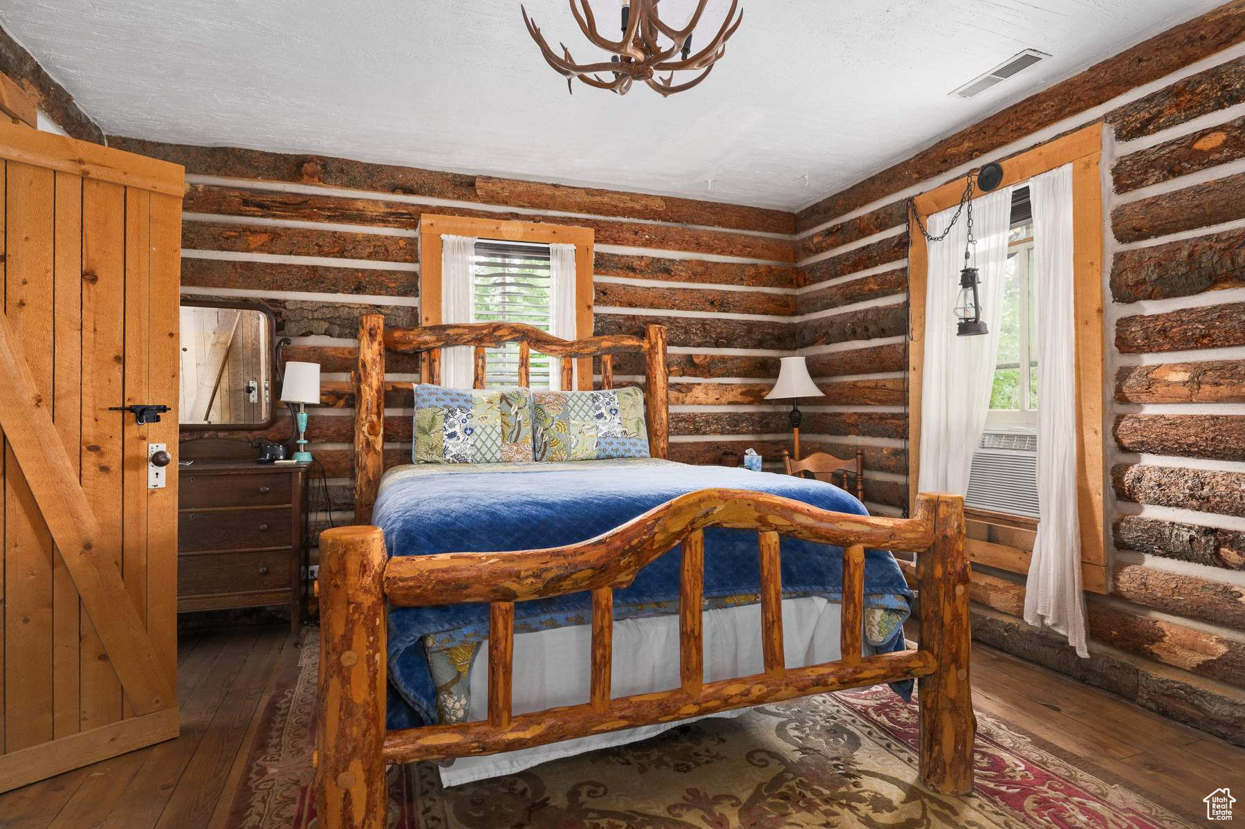 Bedroom featuring rustic walls, a notable chandelier, and hardwood / wood-style floors