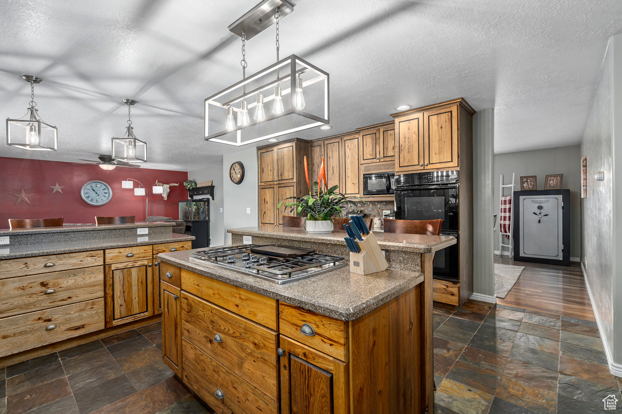 Kitchen featuring pendant lighting, dark tile floors, black appliances, a kitchen island, and ceiling fan