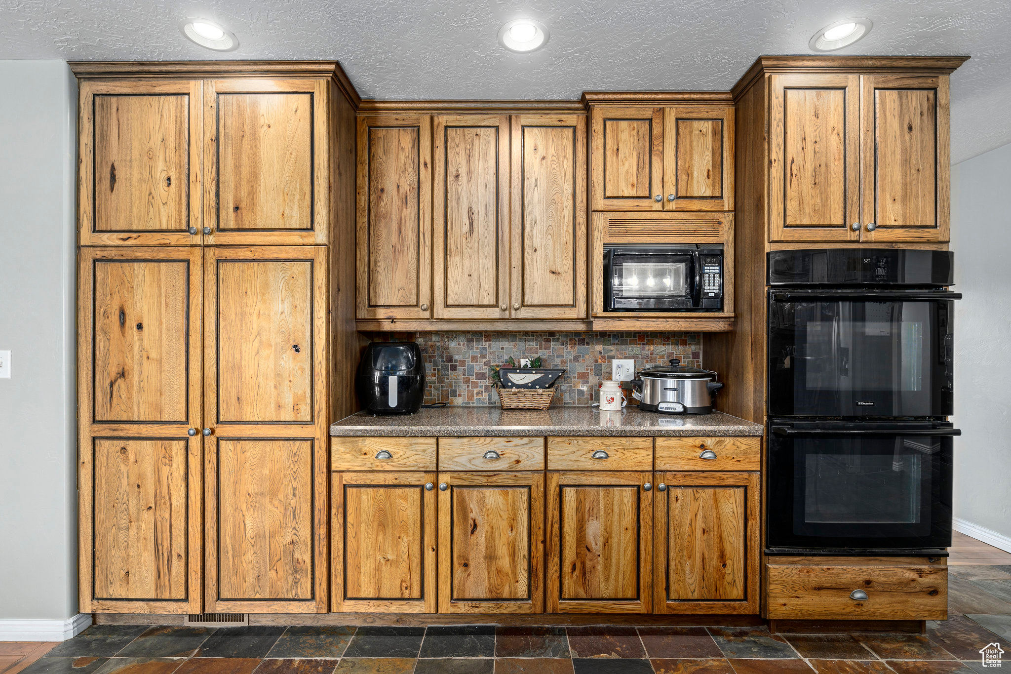 Kitchen featuring tasteful backsplash, black appliances, and a textured ceiling