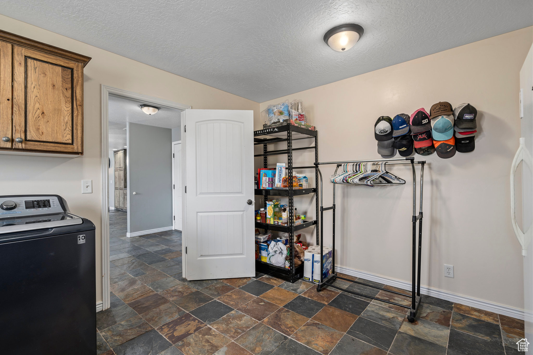 Interior space featuring washer / dryer, dark tile flooring, and a textured ceiling