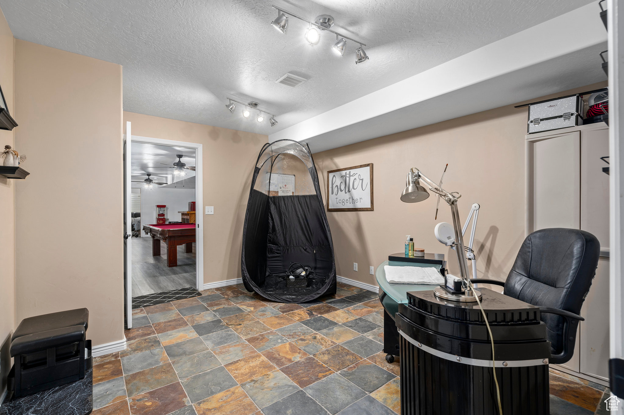 Interior space with dark tile floors, rail lighting, pool table, ceiling fan, and a textured ceiling