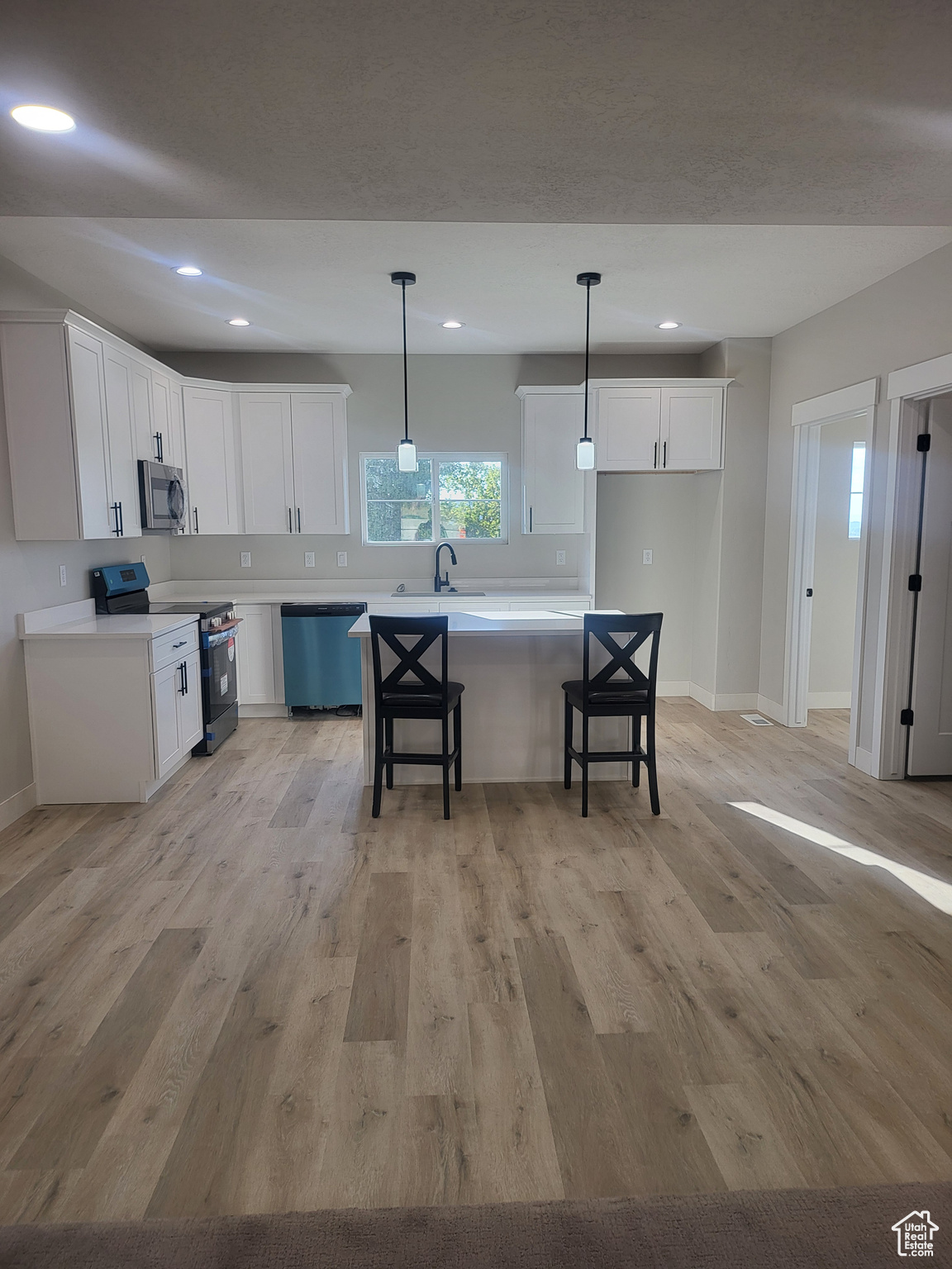 Kitchen with light hardwood / wood-style flooring, appliances with stainless steel finishes, and white cabinetry