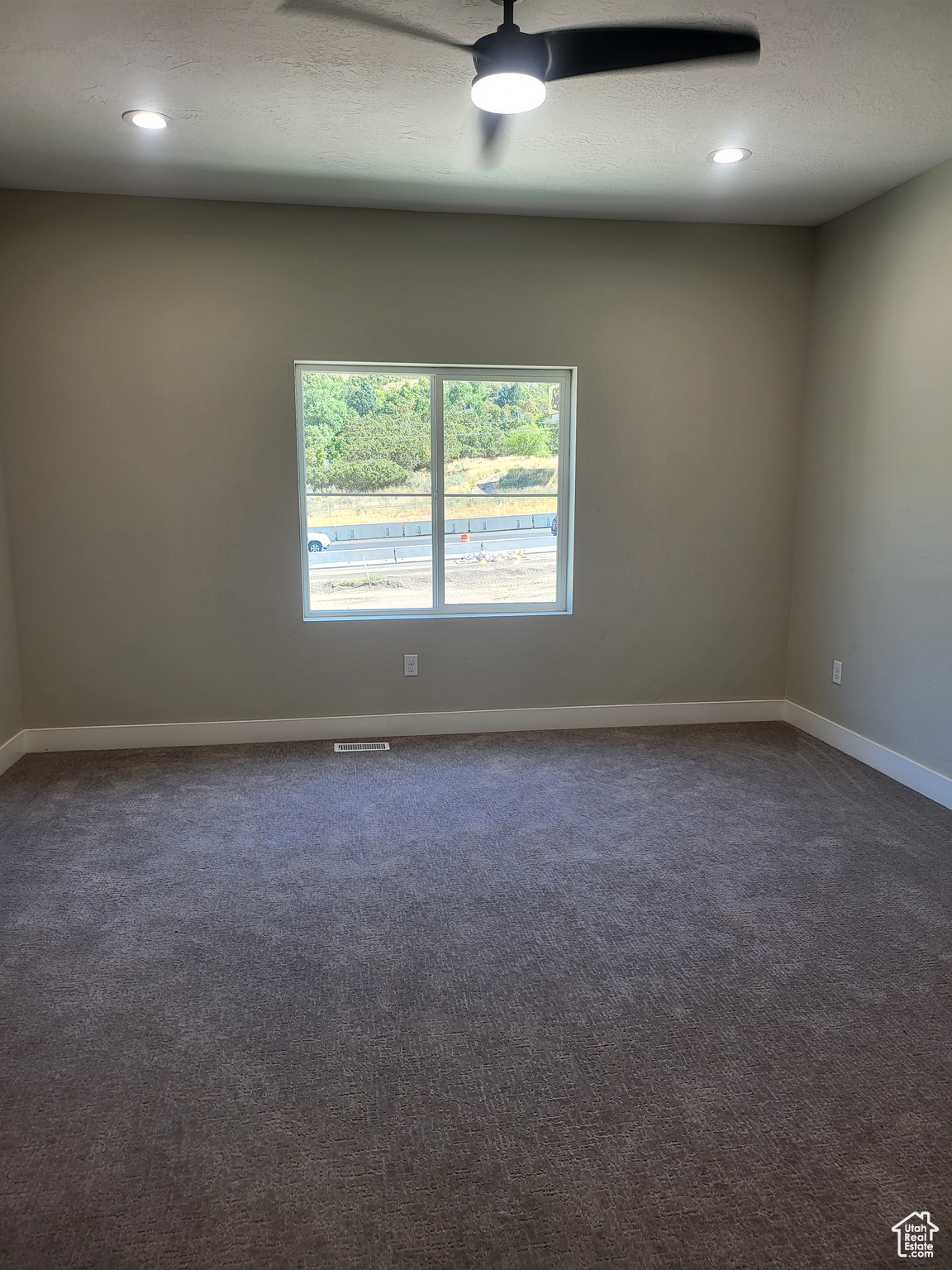 Master bedroom featuring ceiling fan, a textured ceiling, and dark colored carpet